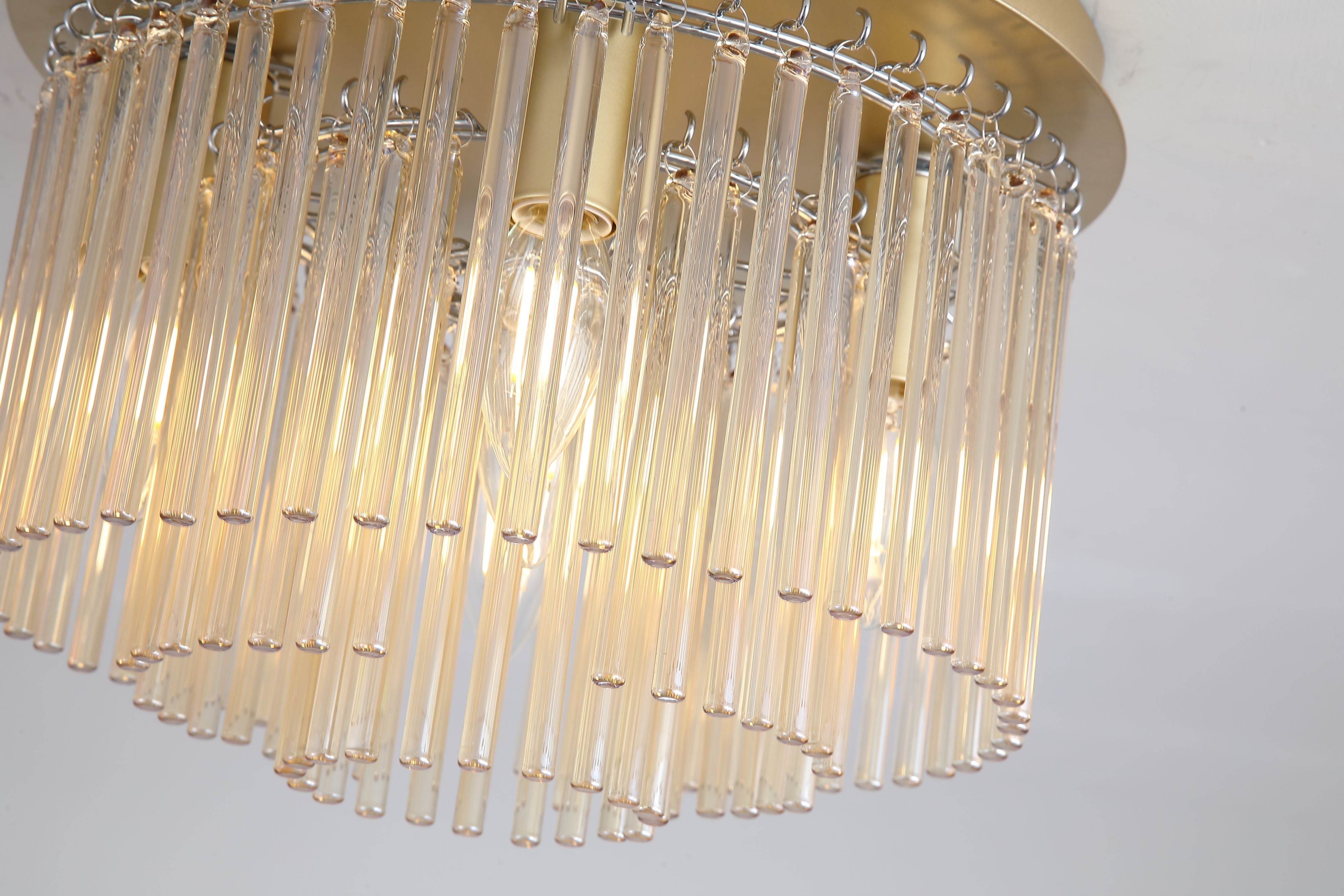 Close up from below of the Swizzle 5 light flush, champagne glass rods, gold ceiling plate and lit candle bulbs
