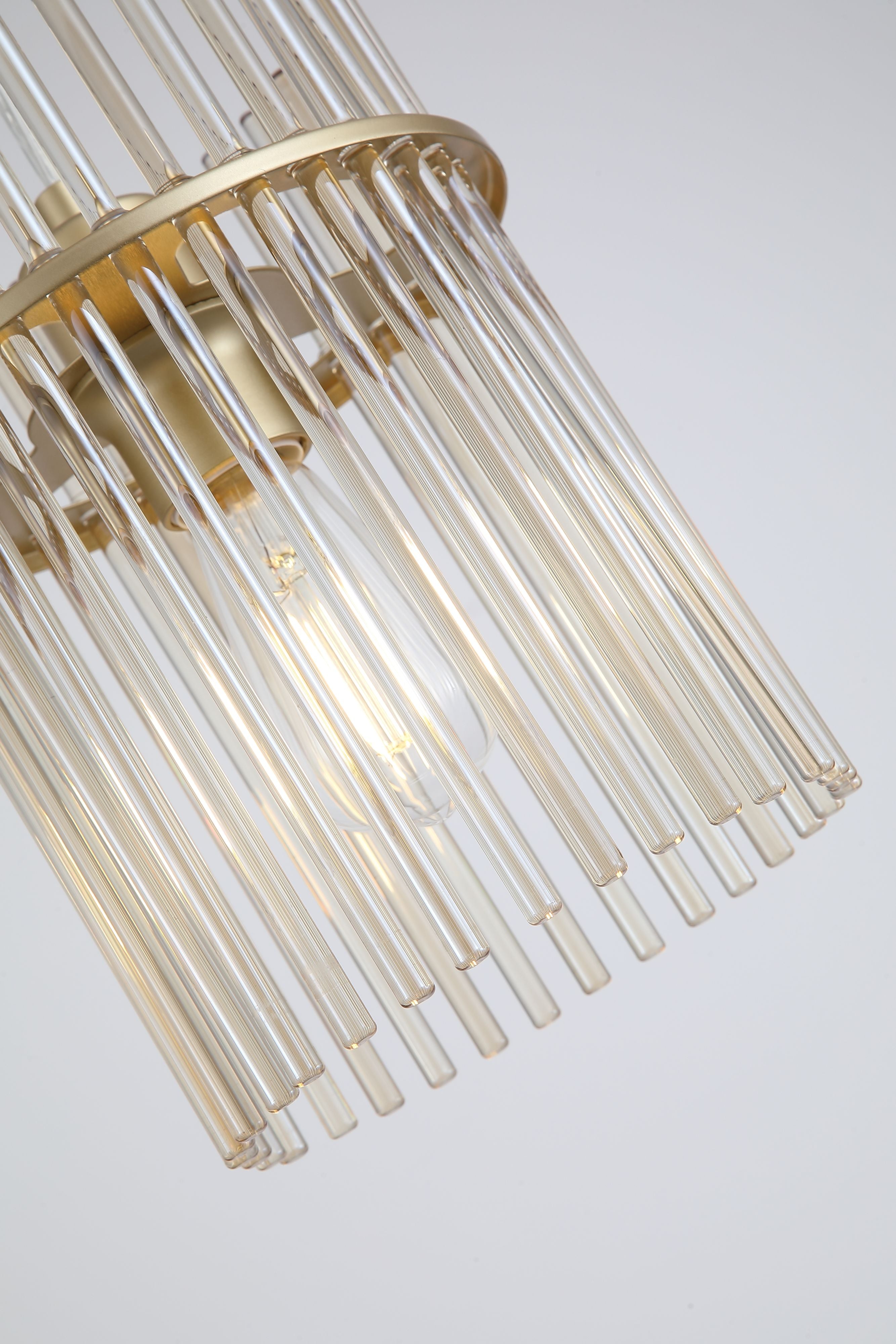 Close up angled detail of the Swizzle 20cm pendant shade showing the individual champagne tinted glass rods and gold frame around the lit bulb