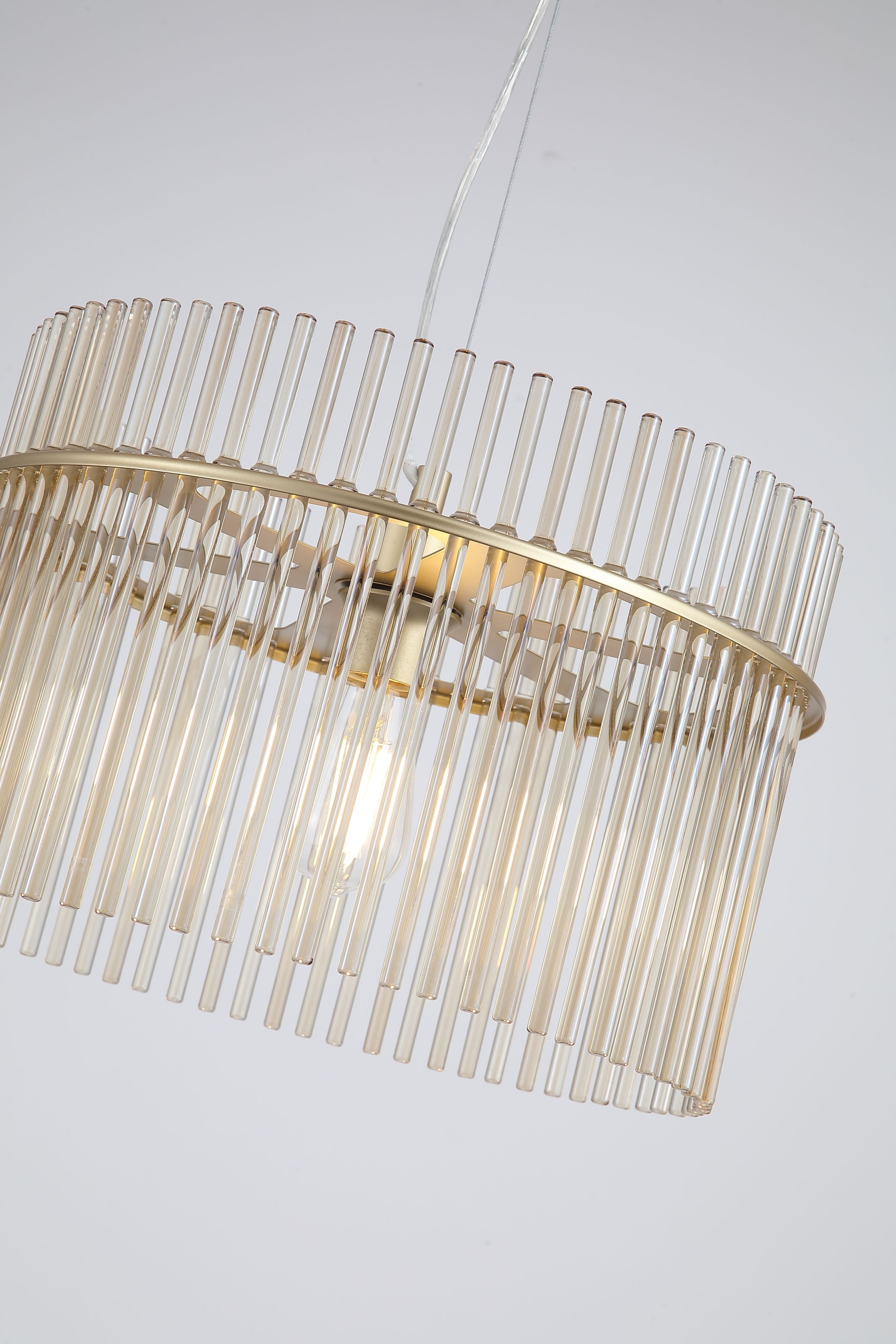 Close up angled detail of the Swizzle 40cm pendant shade showing the individual champagne tinted glass rods and gold frame around the lit bulb