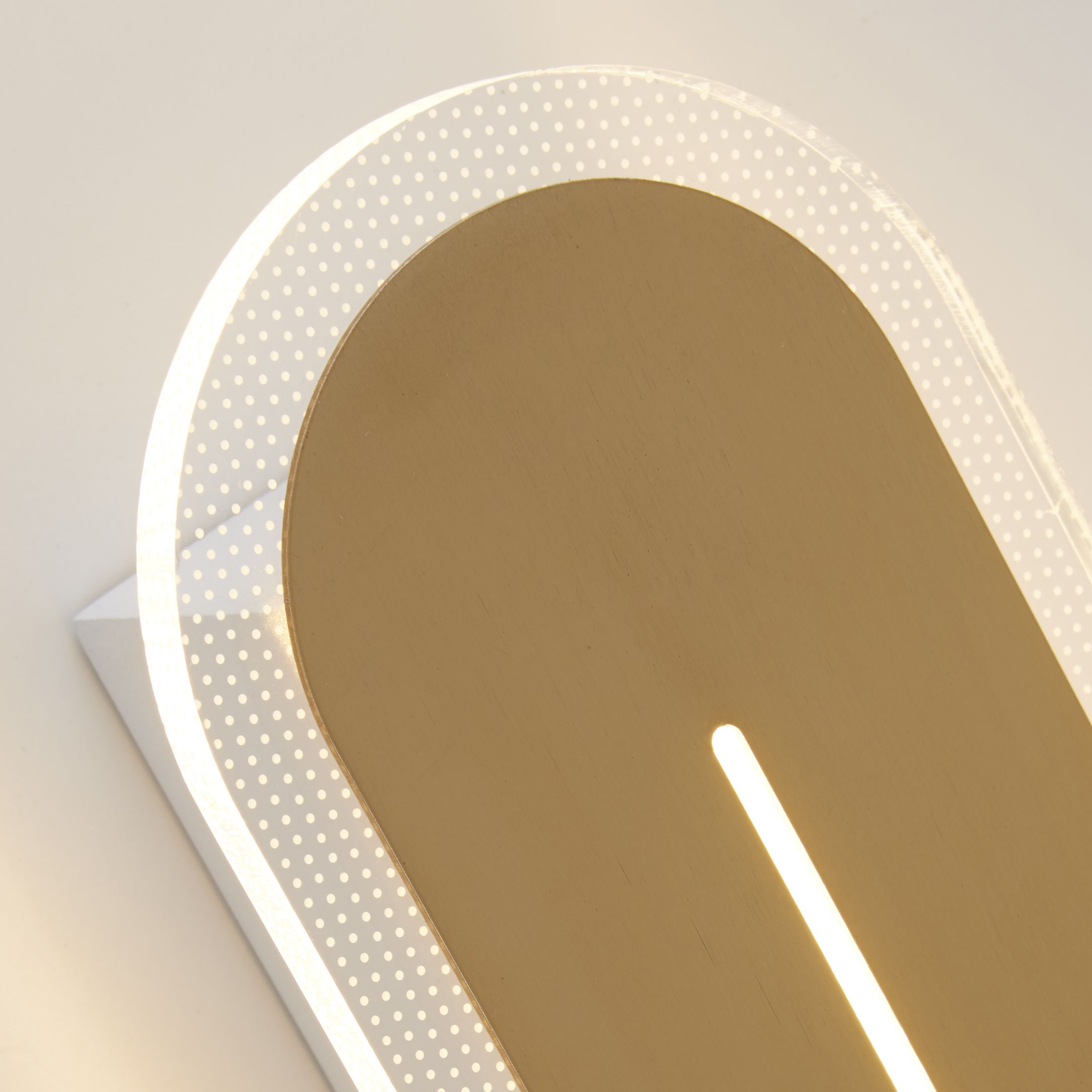 Close up of the Couper wall light's satin brass panel and vertical LED slit set within the white acrylic frame