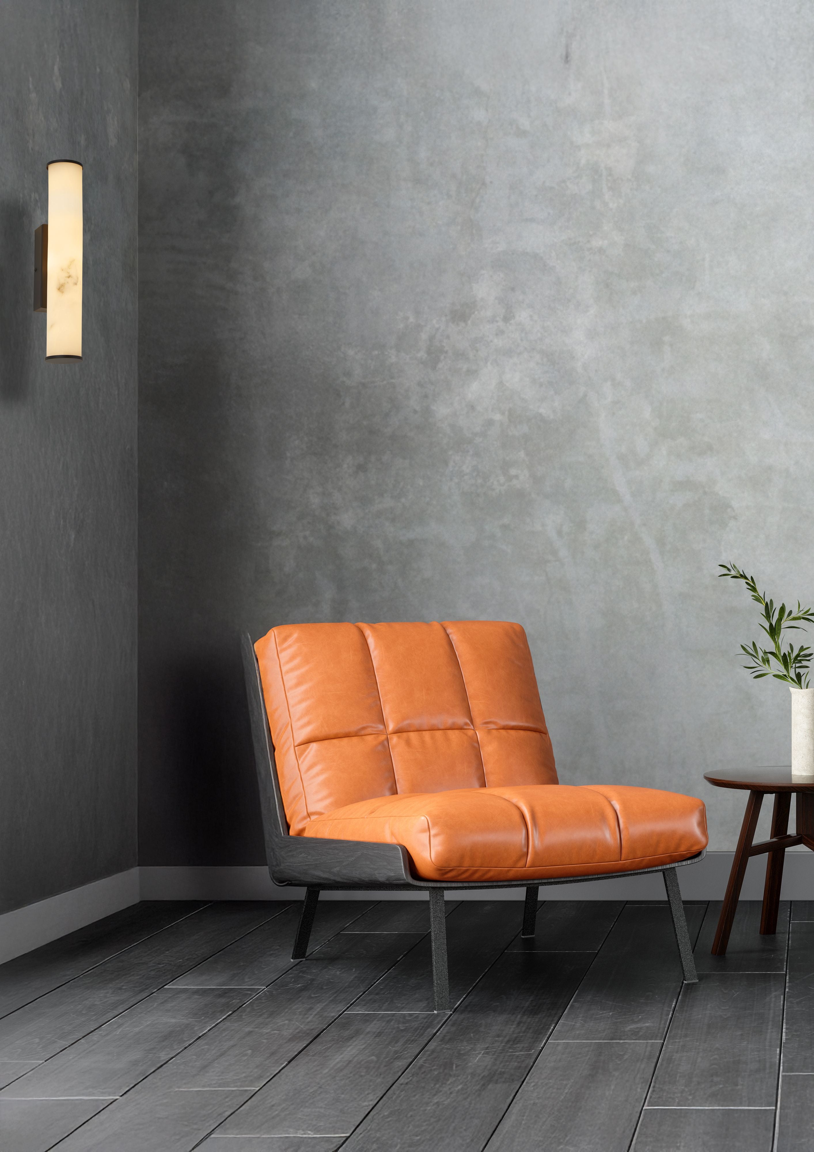 Matt black Wales wall light mounted on a dark grey wall beside an orange leather lounge chair in a styled living room