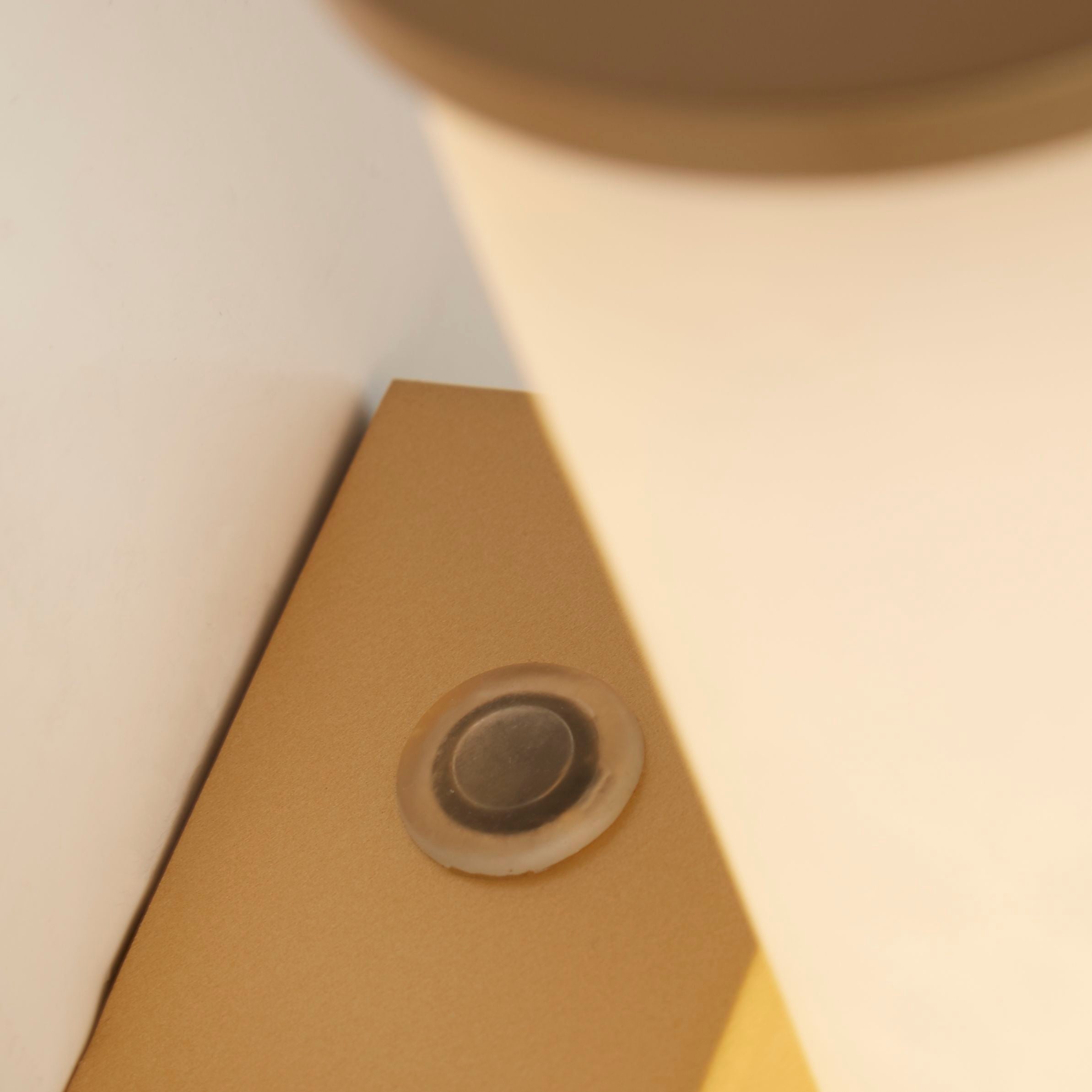 Close up of the gold Wales wall light's rectangular back plate and fixing screw
