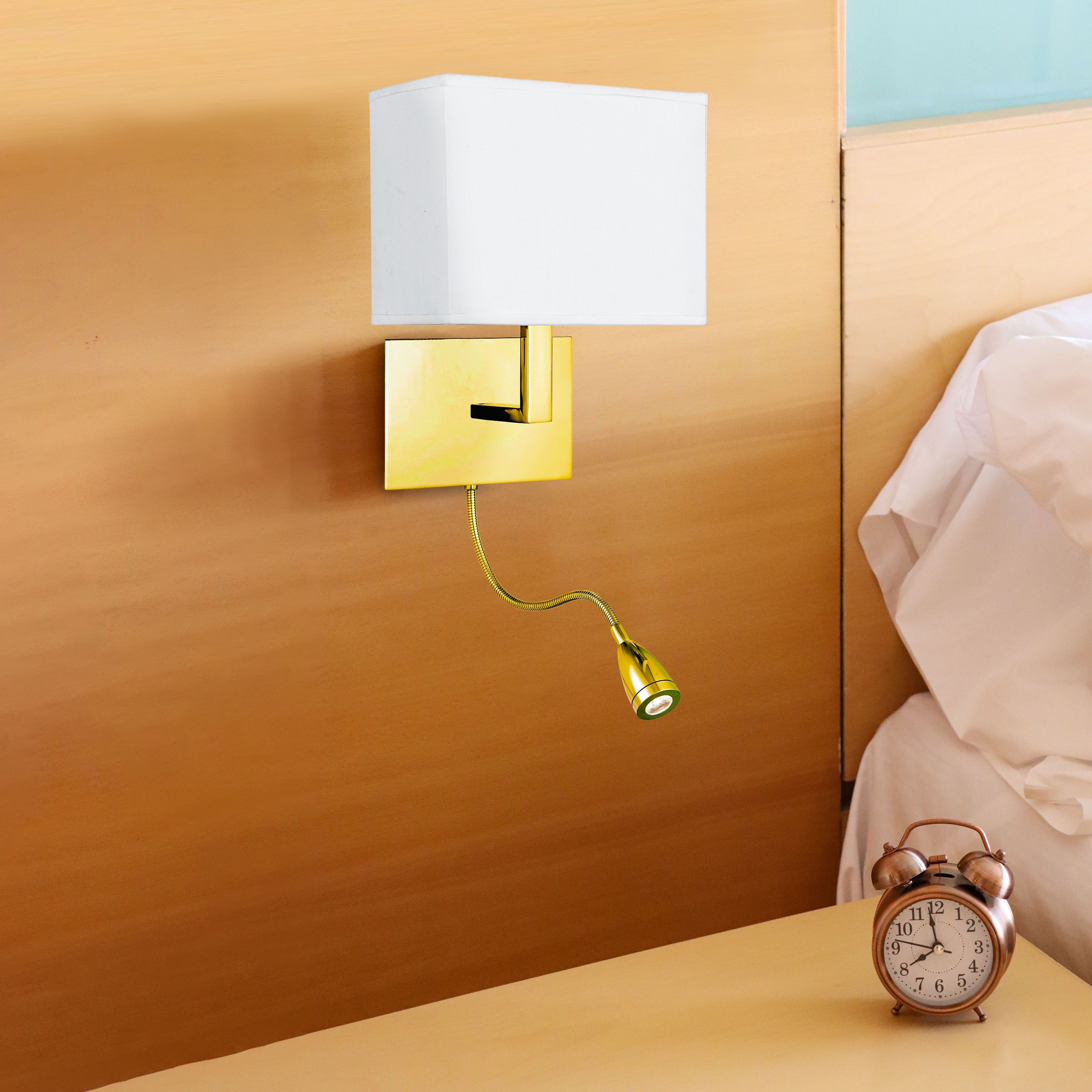 Searchlight Hotel Wall Light in satin brass mounted above a bedside table with an alarm clock, reading arm extended toward the bed