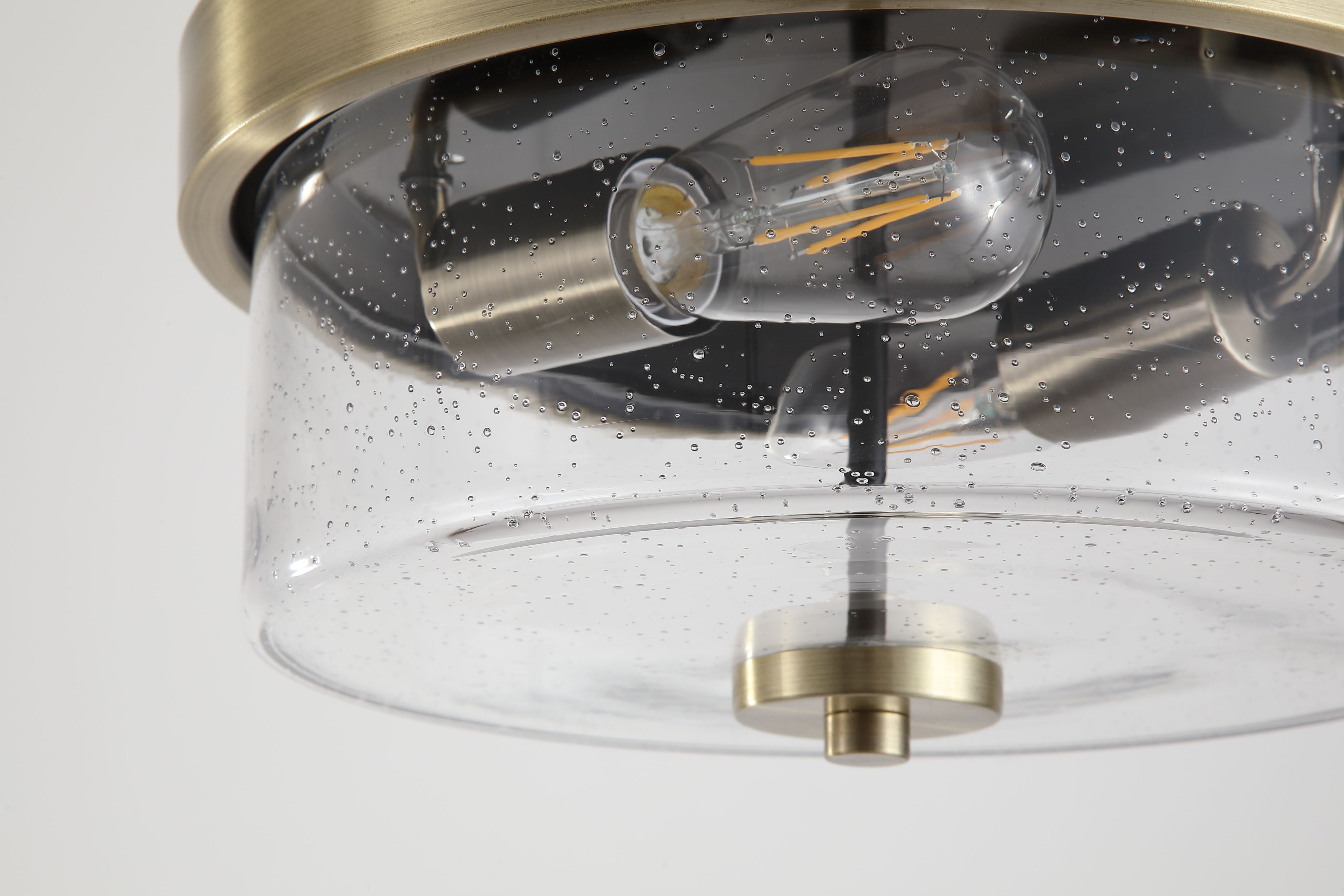 Close up of the Searchlight Preston's antique brass fitting and filament bulb through the seeded glass drum