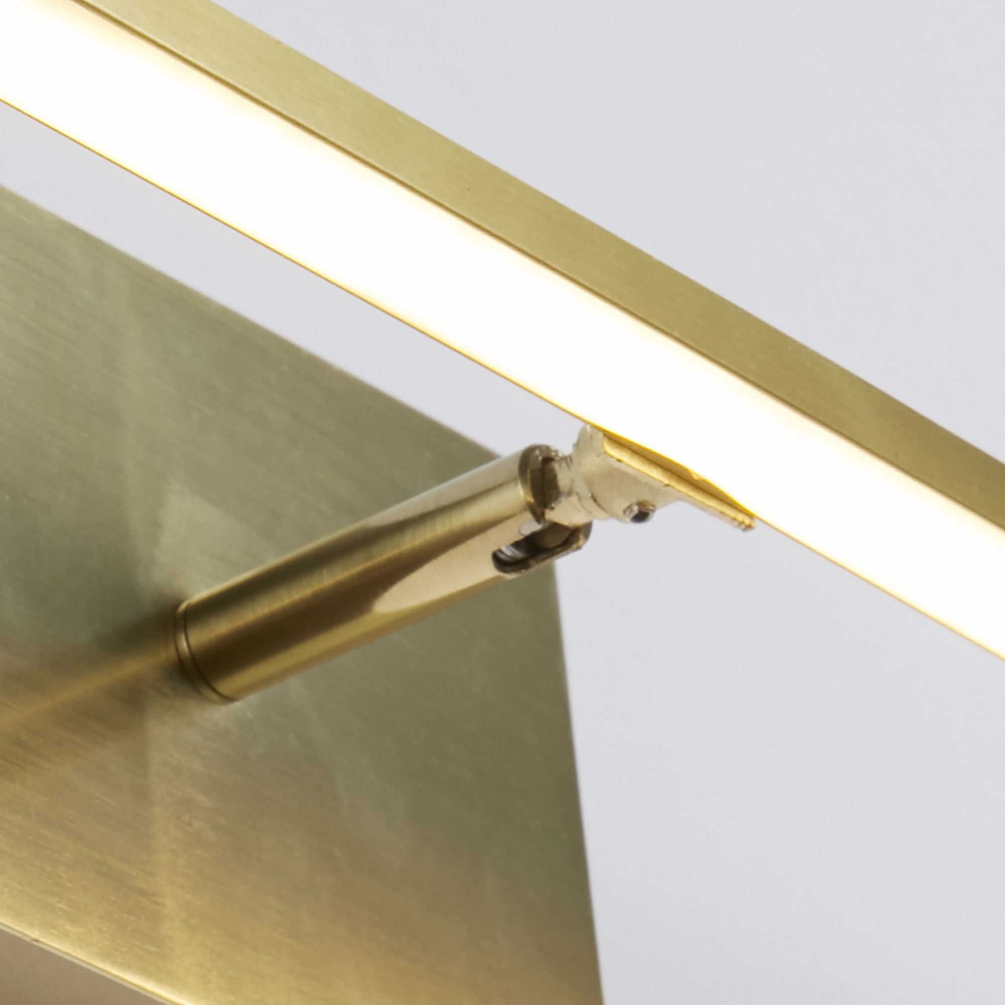 Close up of the satin brass Amalfi wall light showing the swivel spotlight beneath the bar and the brushed metal backplate
