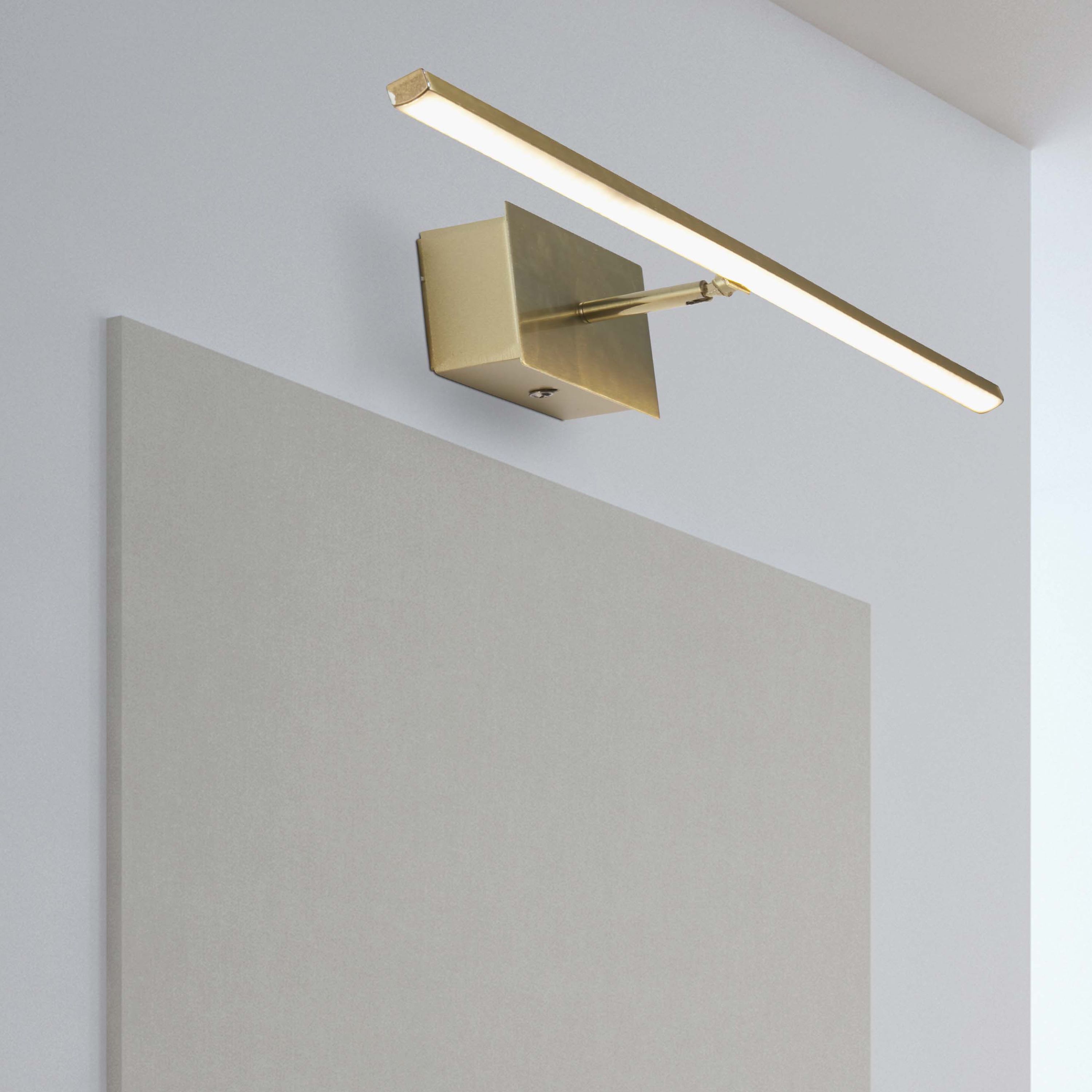 Amalfi 41cm LED wall light in satin brass installed above a bathroom mirror, illuminated with a warm white glow
