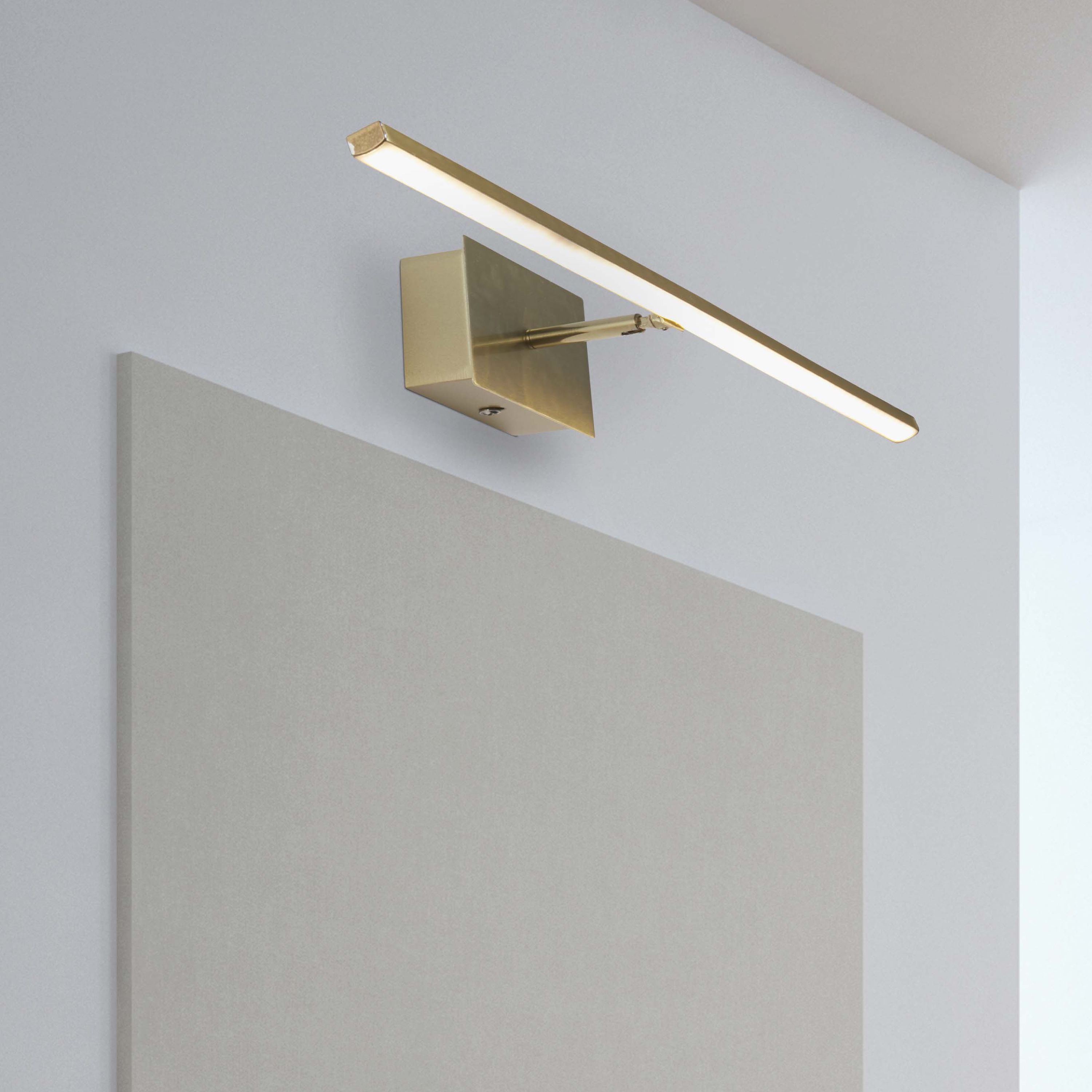 Amalfi 61cm LED wall light in satin brass installed above a bathroom mirror, illuminated with a warm white glow