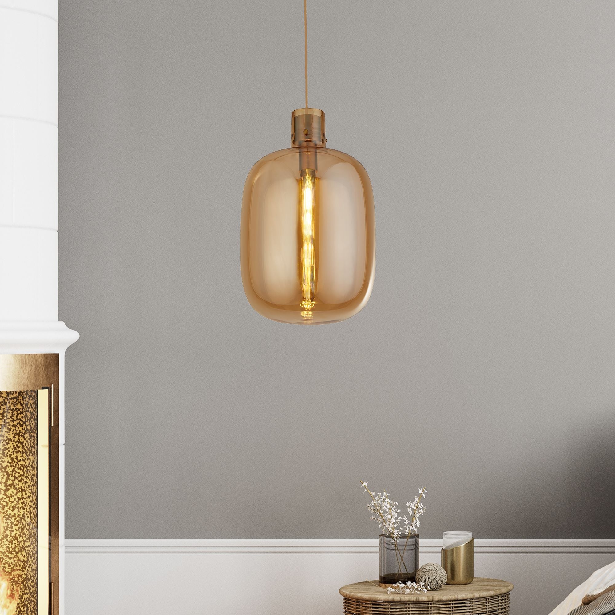Searchlight Barrel pendant light lit and hanging in a styled living room beside a fireplace and side table