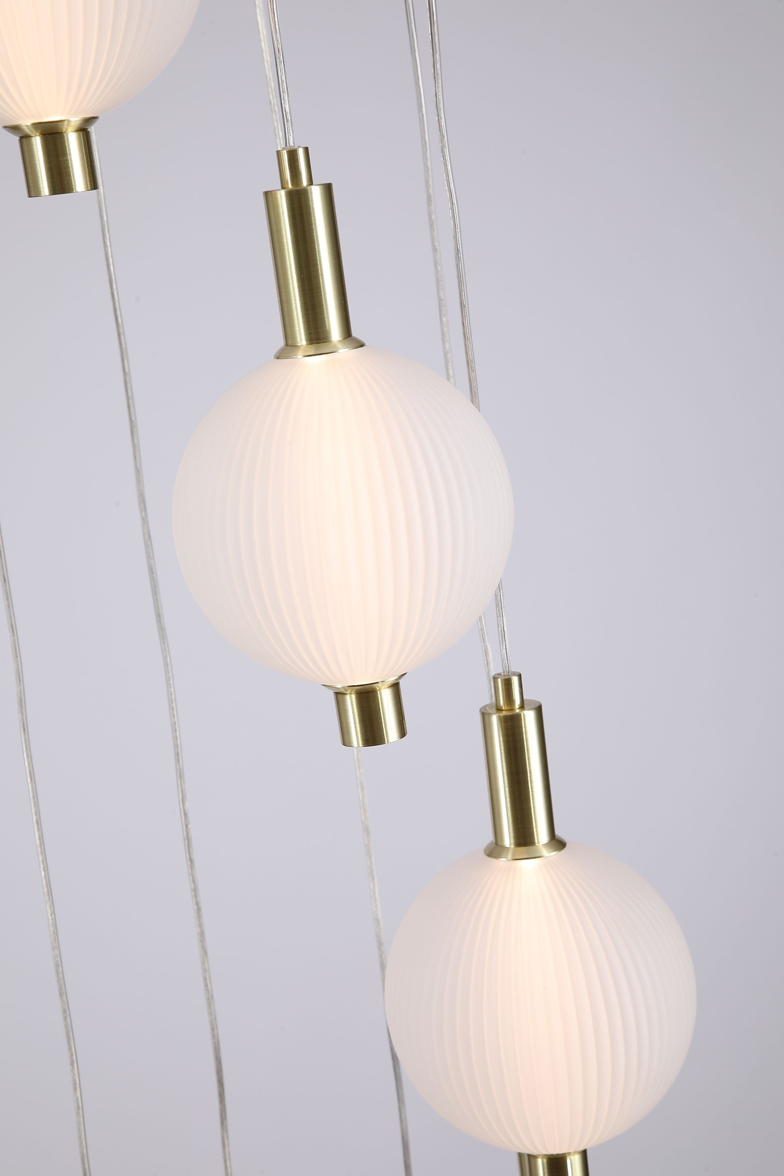 Close up of several ribbed glass globes and satin brass fittings on the Searchlight Luminique LED 8 Light Pendant