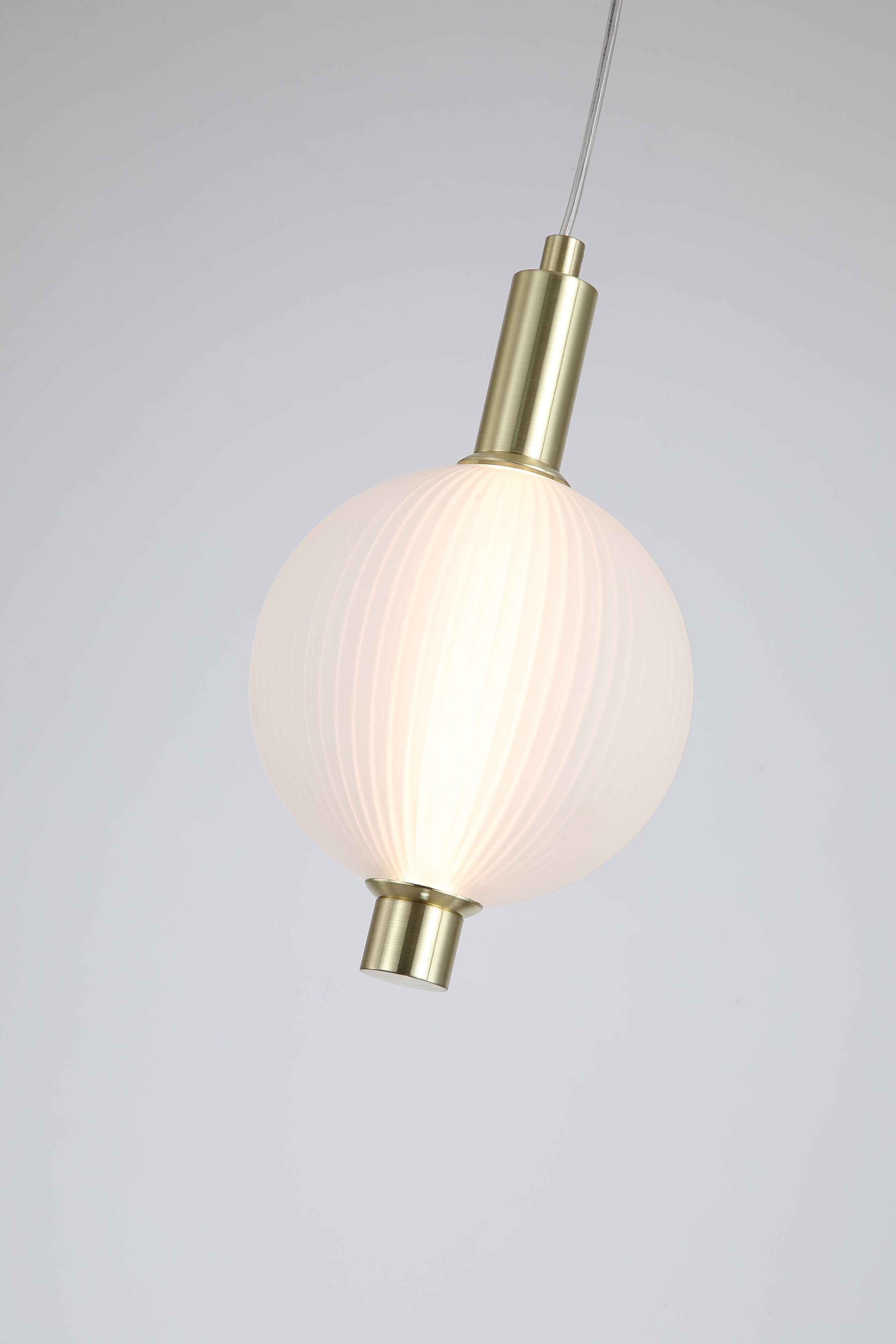 Close up of the Searchlight Luminique LED Pendant in satin brass, showing the ribbed glass globe and satin brass fittings at the top and base of the shade