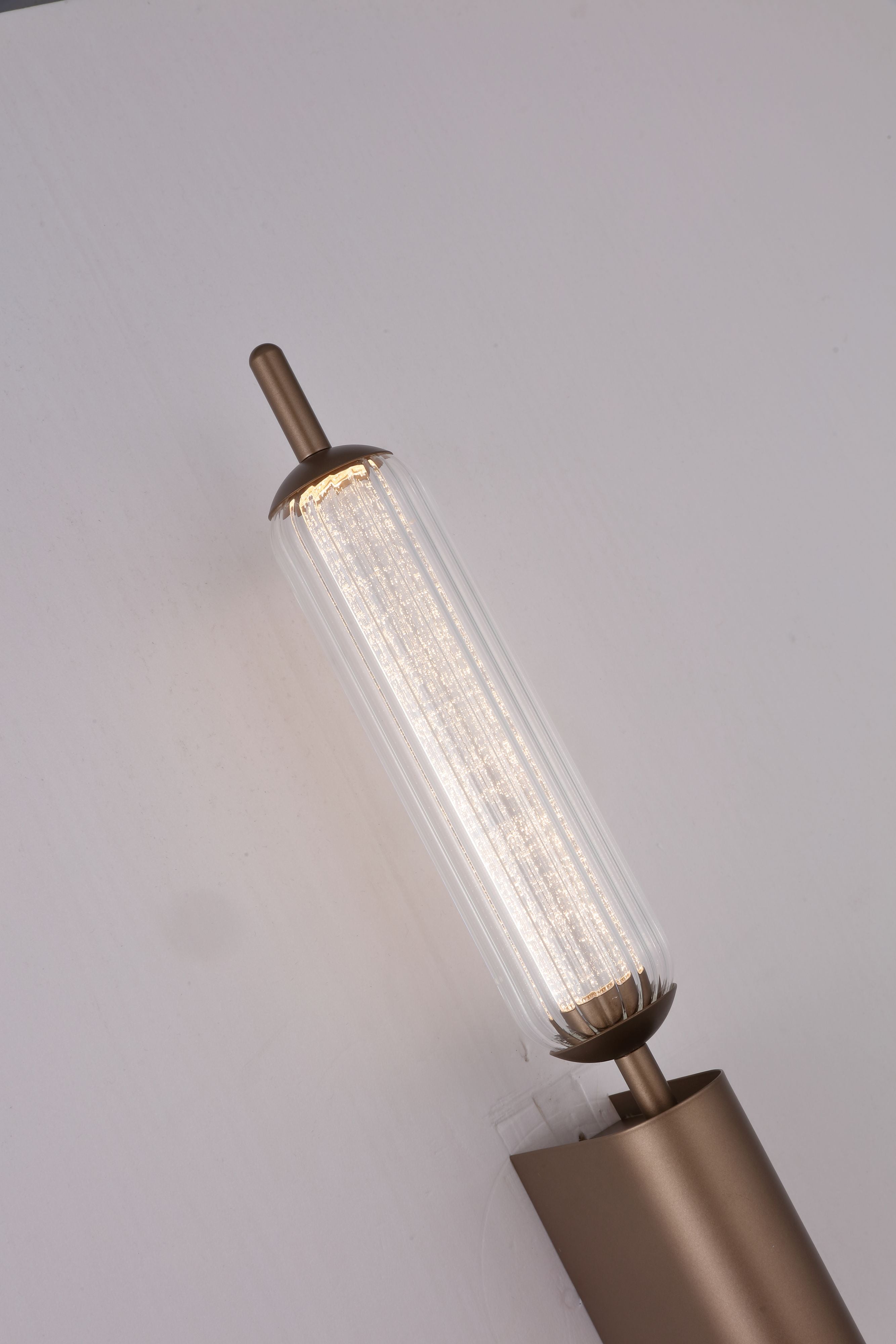 Close up angled view of the Searchlight Cattail LED Wall Lamp showing the ribbed glass tube lit and the latte metal end cap