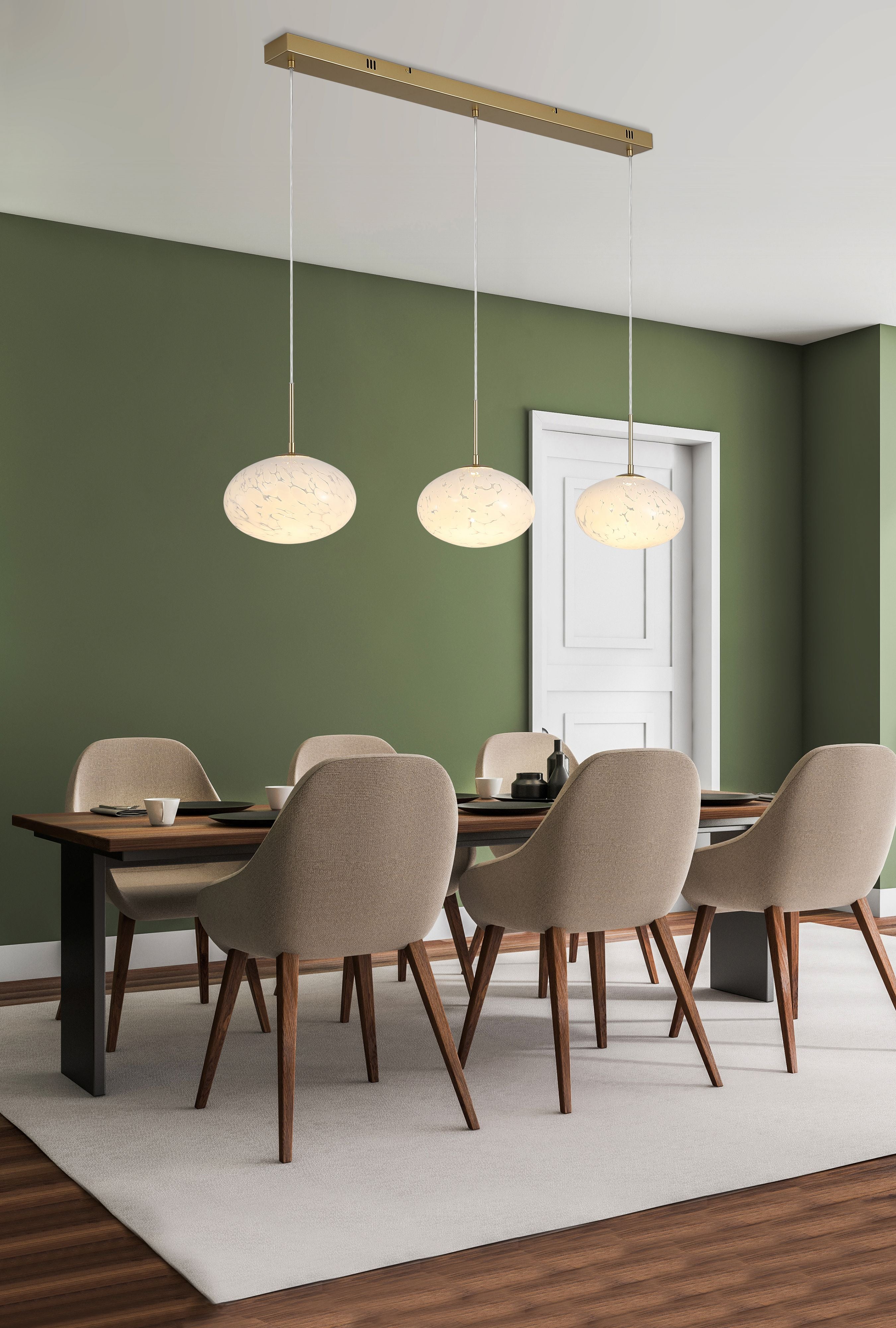 Three gold Confetti LED pendants with confetti glass shades hanging above a dining table against a green wall
