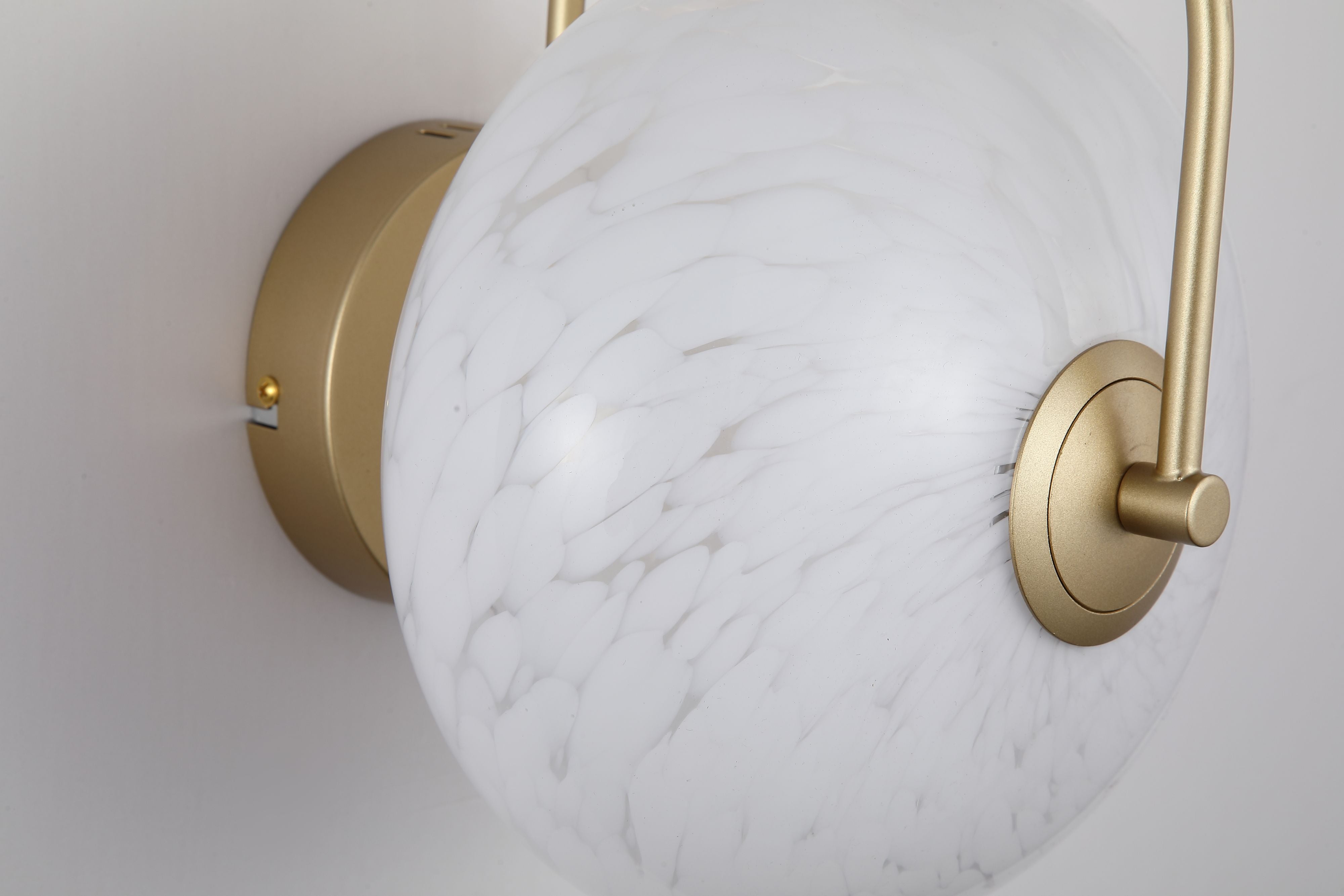 Close up angled view of the Searchlight Confetti LED Wall Light showing the gold backplate, curved arm and mottled confetti glass texture