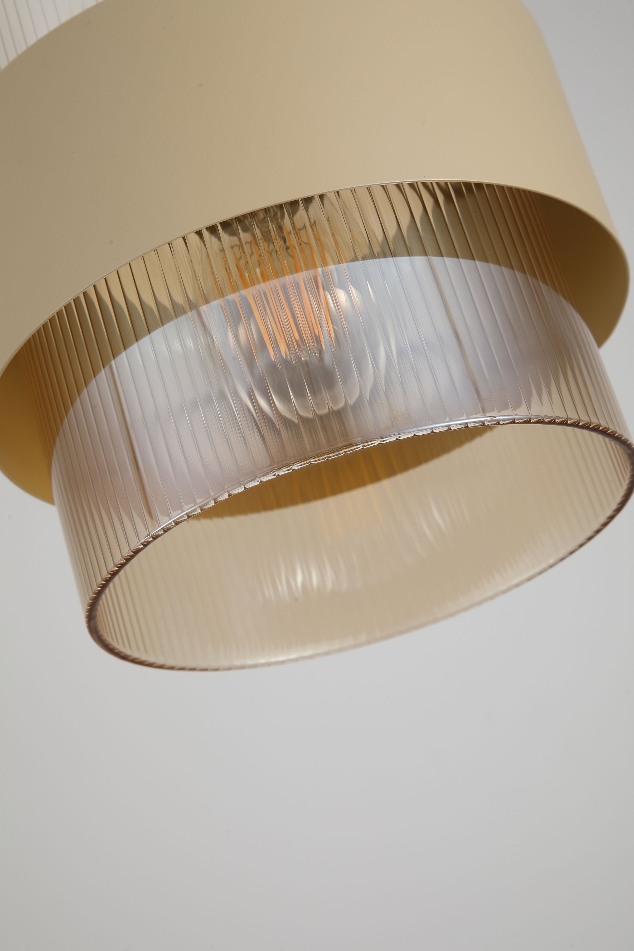 Close up of the Searchlight Royal Pendant showing the ribbed amber glass texture and sand metal band lit from within