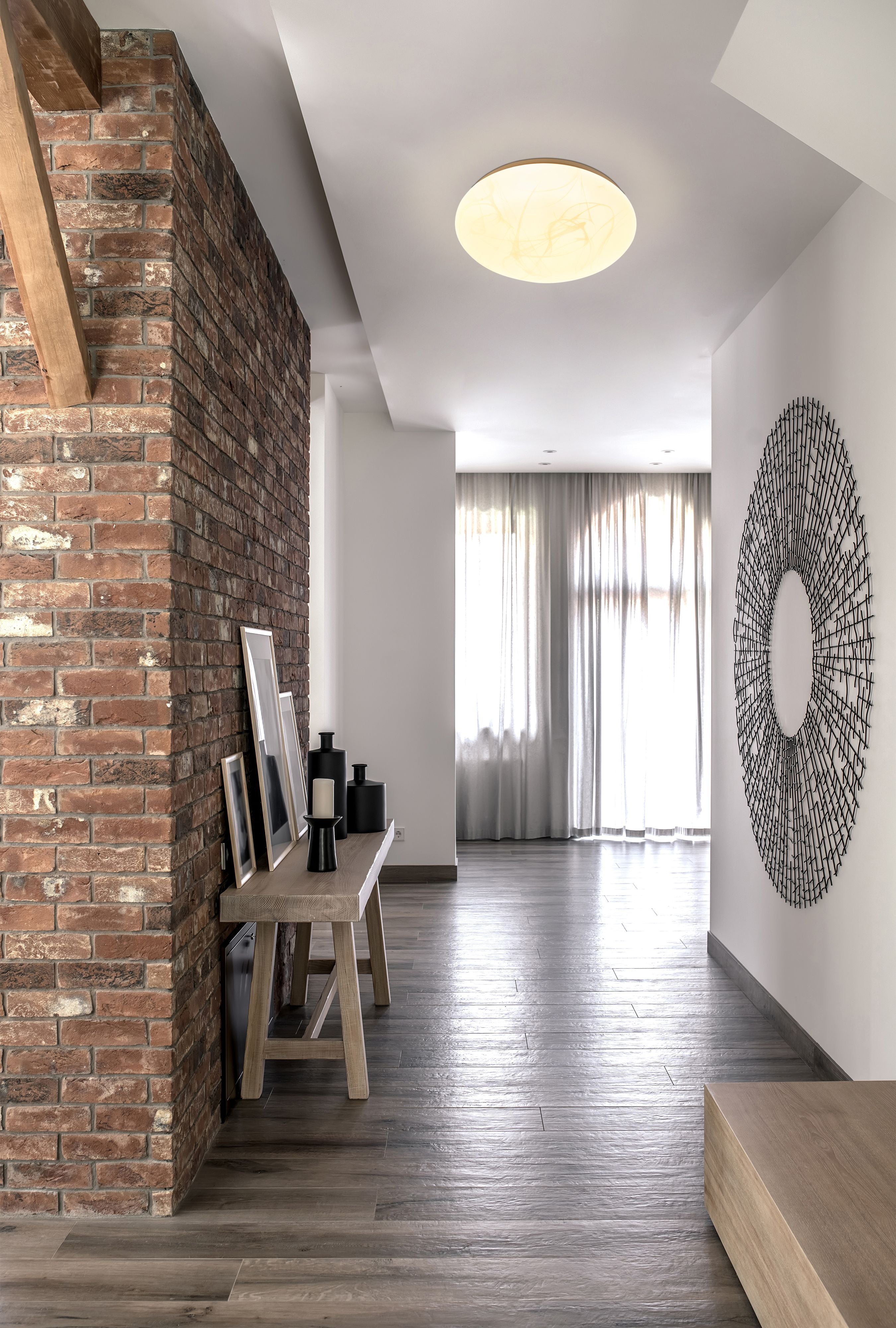 Searchlight Maya LED flush light in white acrylic fitted to the ceiling of a hallway with an exposed brick feature wall