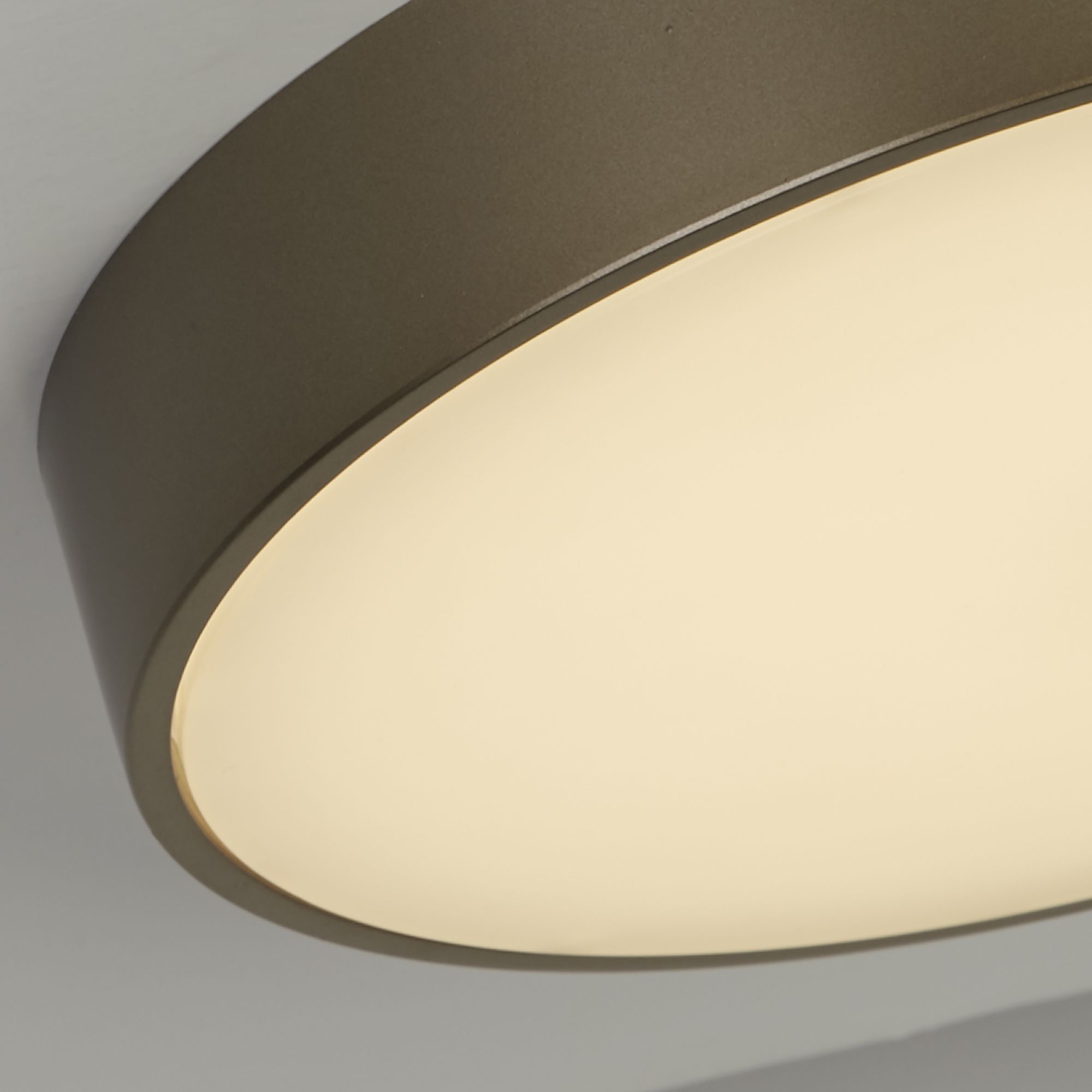 Close up of the Palma flush light's bronze rim and white diffuser edge