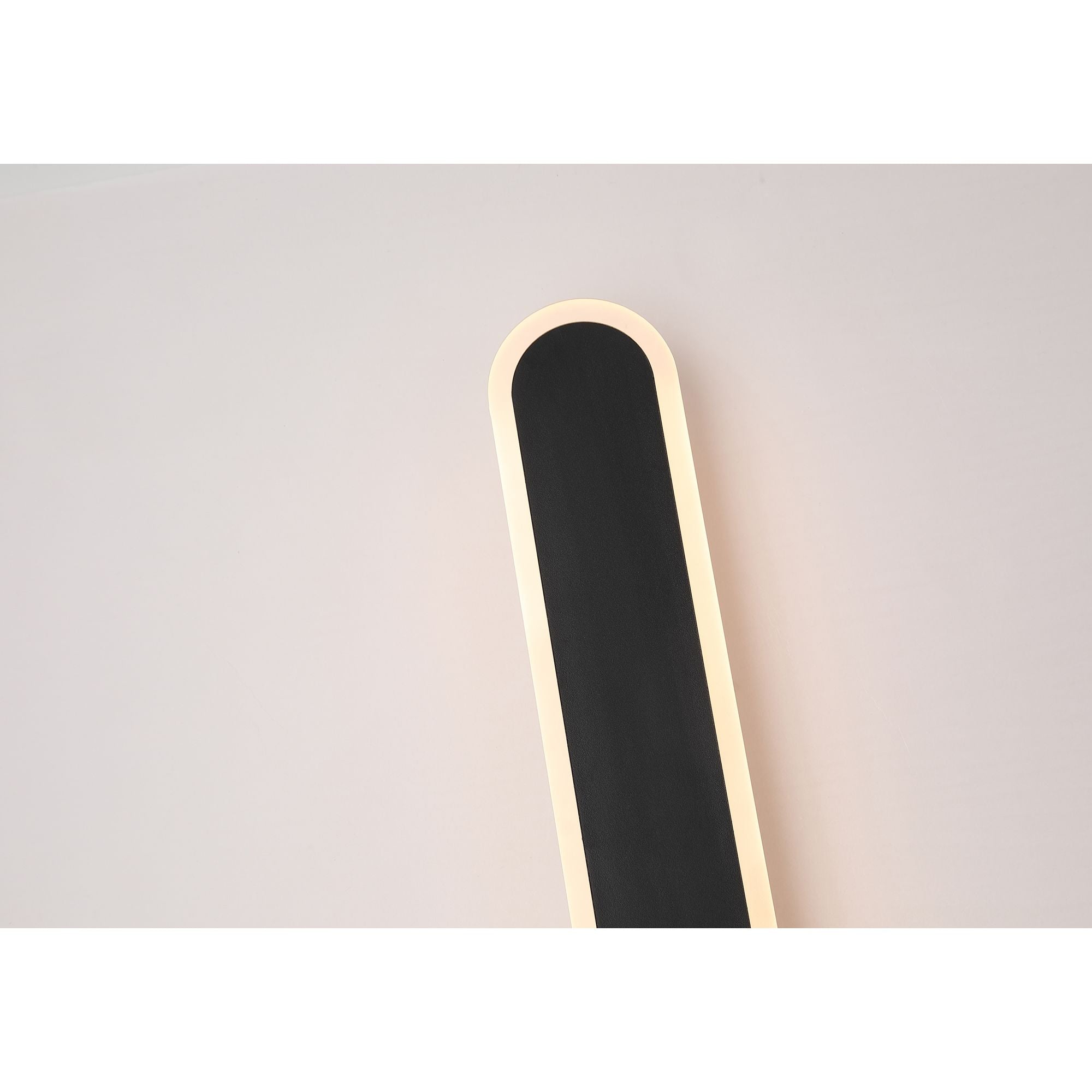 Close up of the rounded top end of the Bordo wall light, lit, mounted on a plain wall