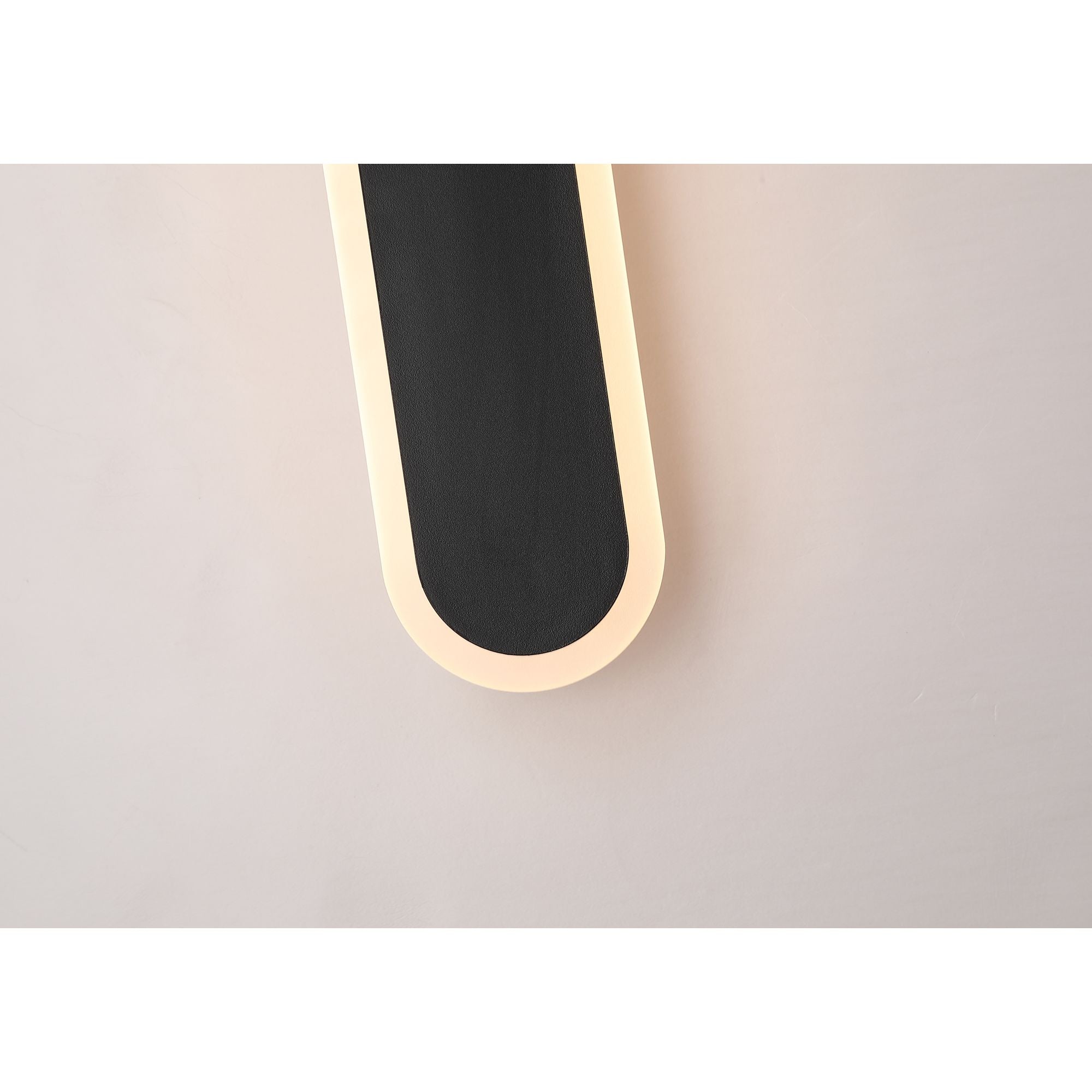 Close up of the top corner of the Bordo LED outdoor wall light in black, lit and mounted on a blush pink exterior wall