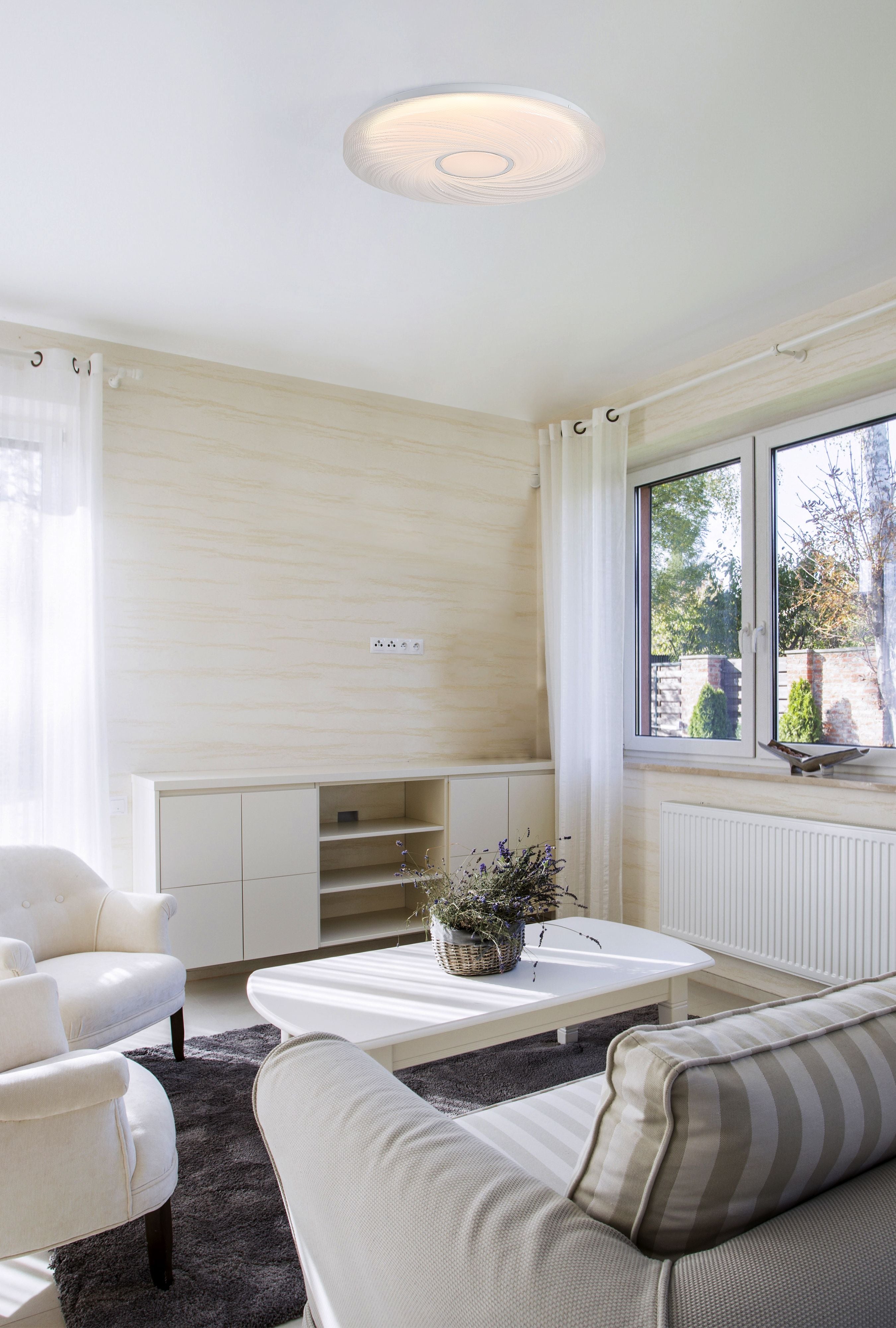 Aura LED flush ceiling light fitted above a white coffee table in a bright neutral toned living room