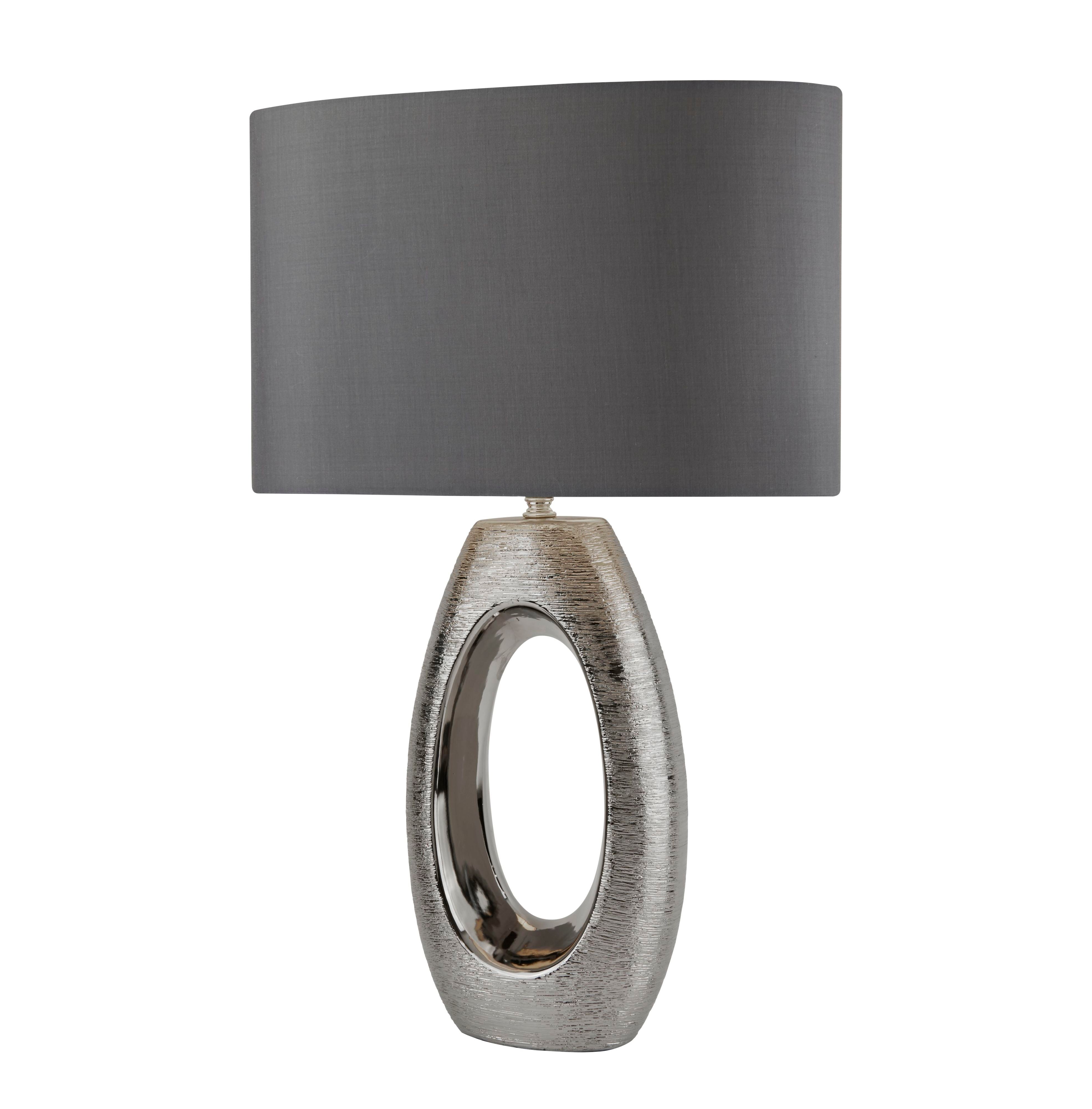 Searchlight Artisan table lamp with brushed silver oval cut out ceramic base and grey faux silk shade, angled studio shot on a white background