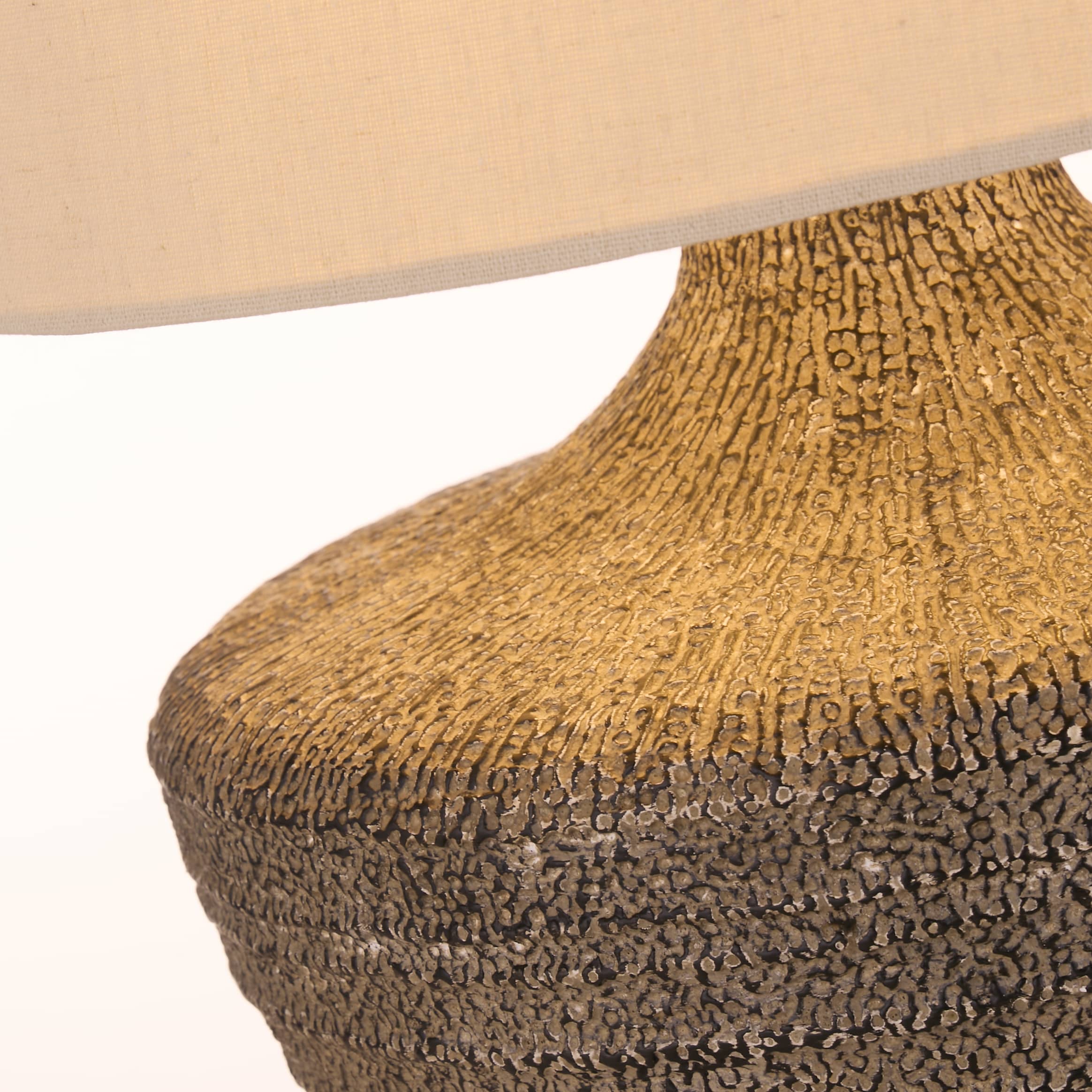 Close up of the Avaya table lamp ribbed ceramic texture, showing the transition from gold at the neck to charcoal grey at the base