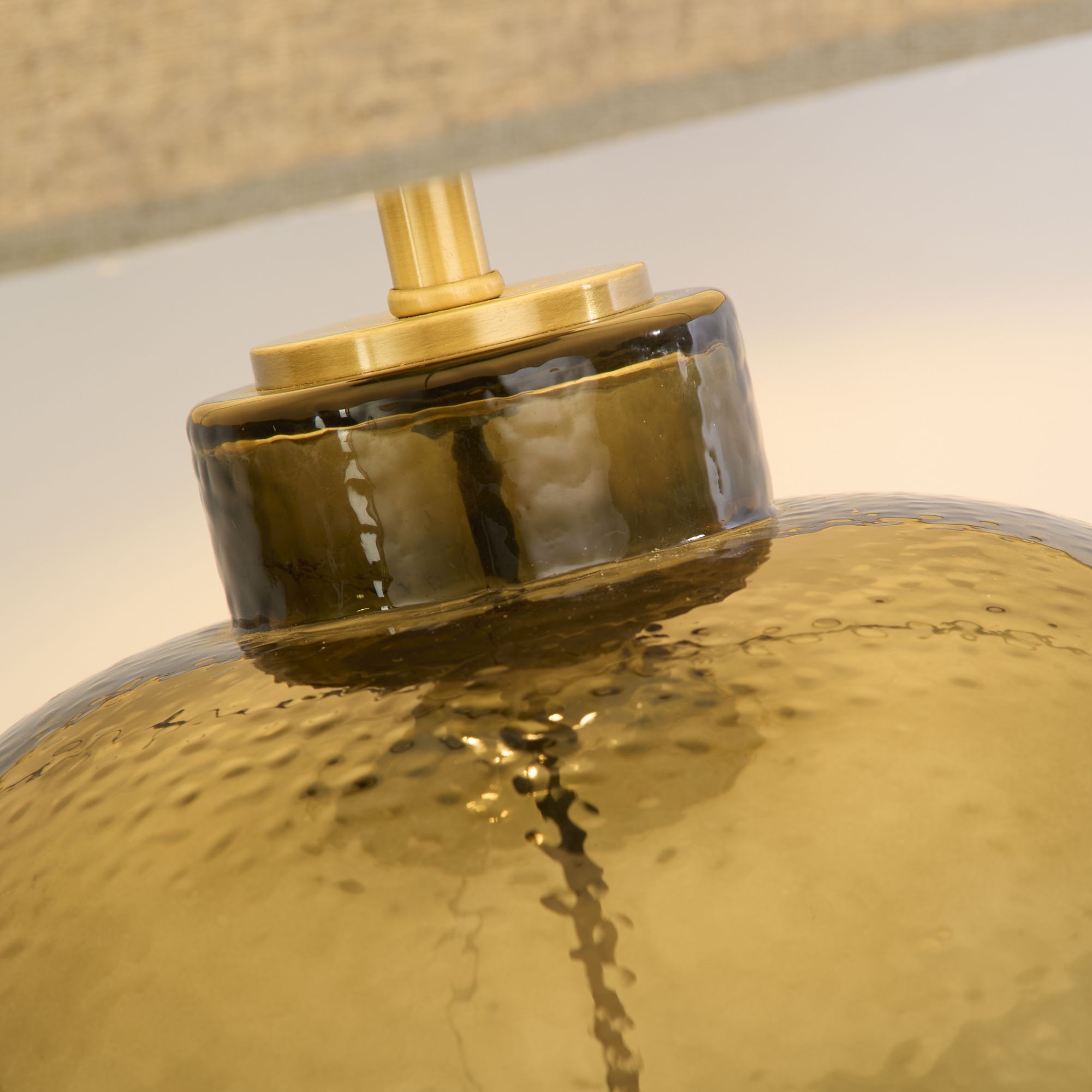 Close up of the Zenith table lamp brass coloured neck collar and hammered green glass texture