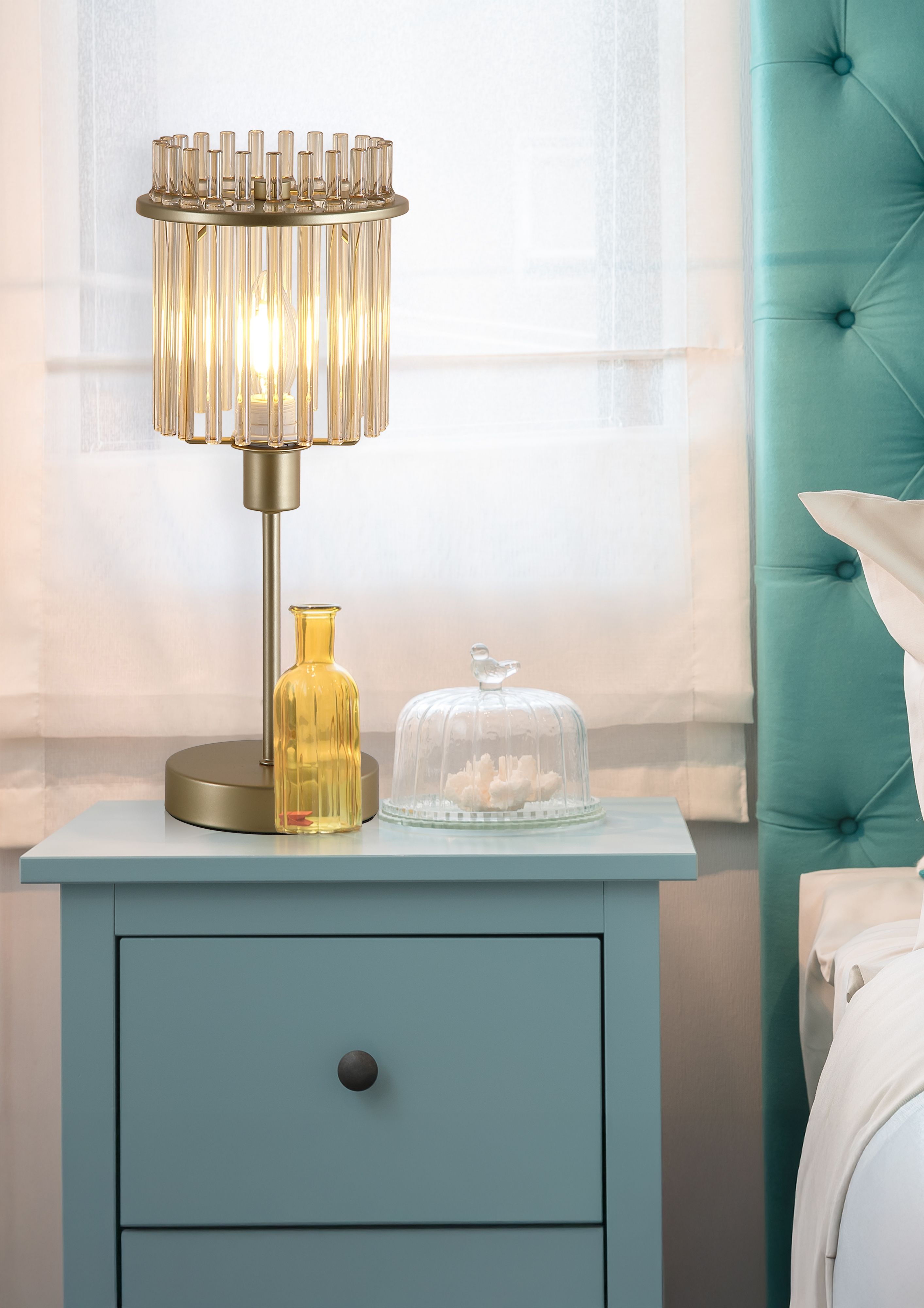 Searchlight Swizzle gold table lamp styled on a blue bedside table next to an amber glass vase and glass cloche