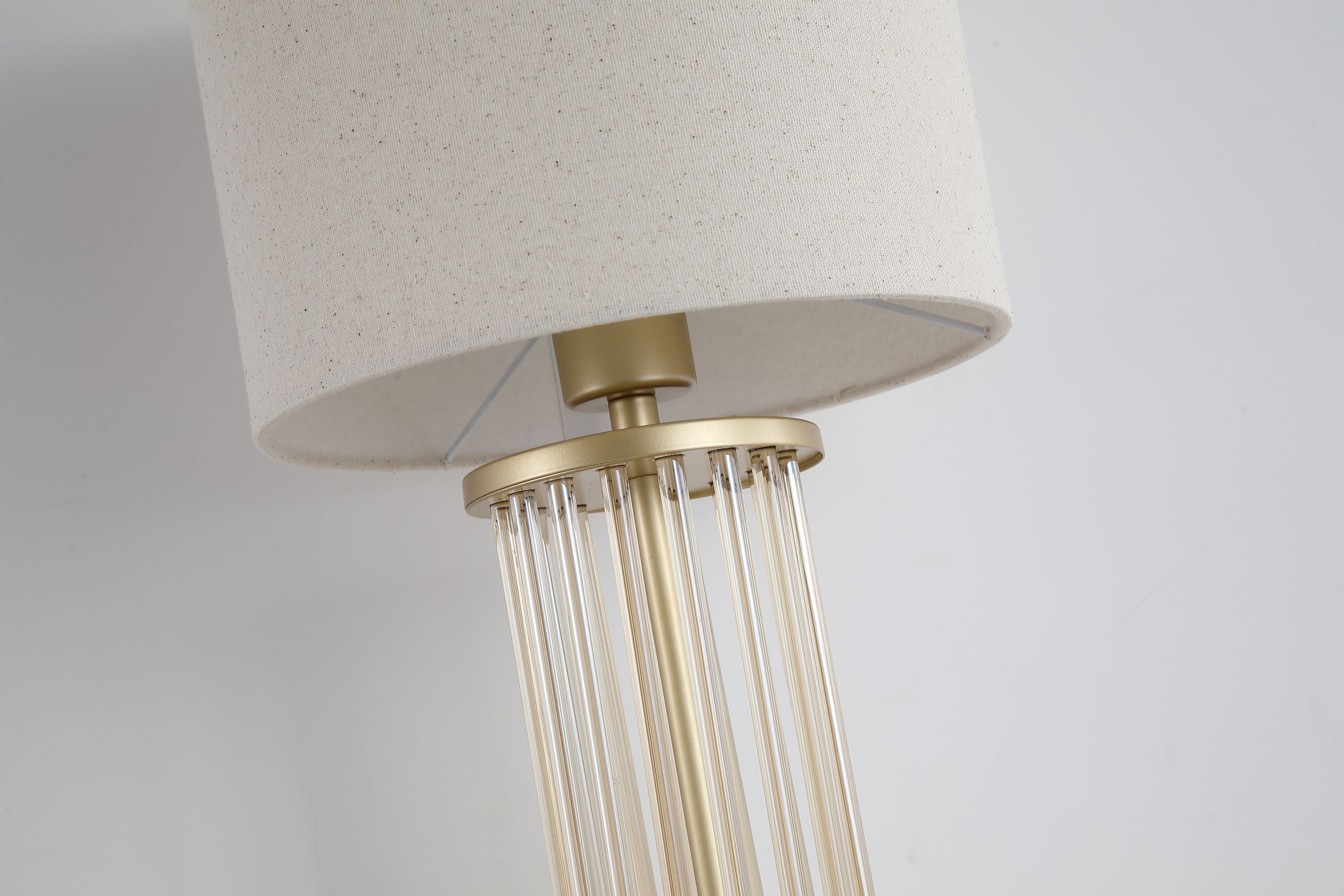 Close up of the Swizzle table lamp gold rod base, showing the glass rods set into the brass finished top and base discs