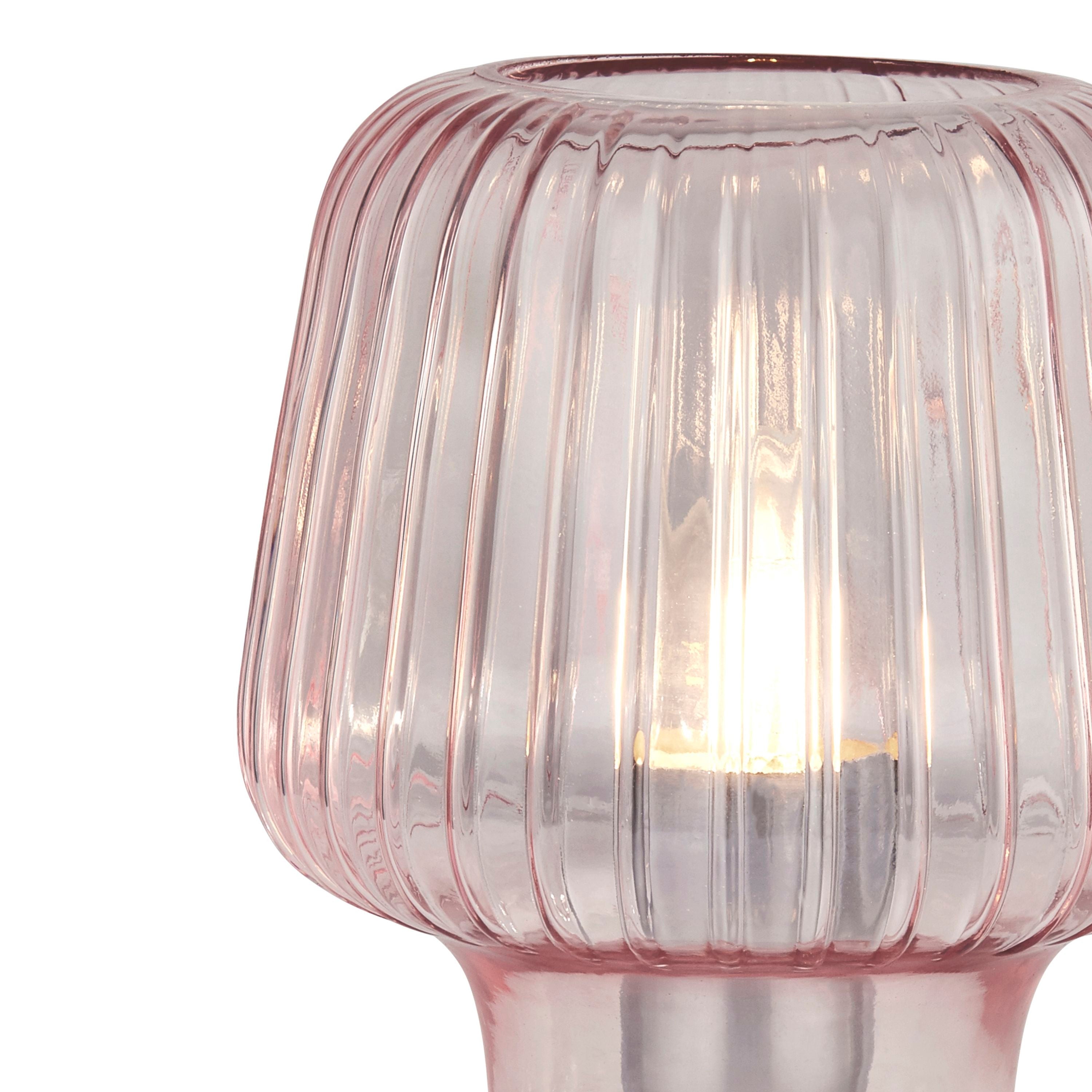 Close up of the Searchlight Aria table lamp showing the ribbed texture of the pink glass and the lit bulb inside