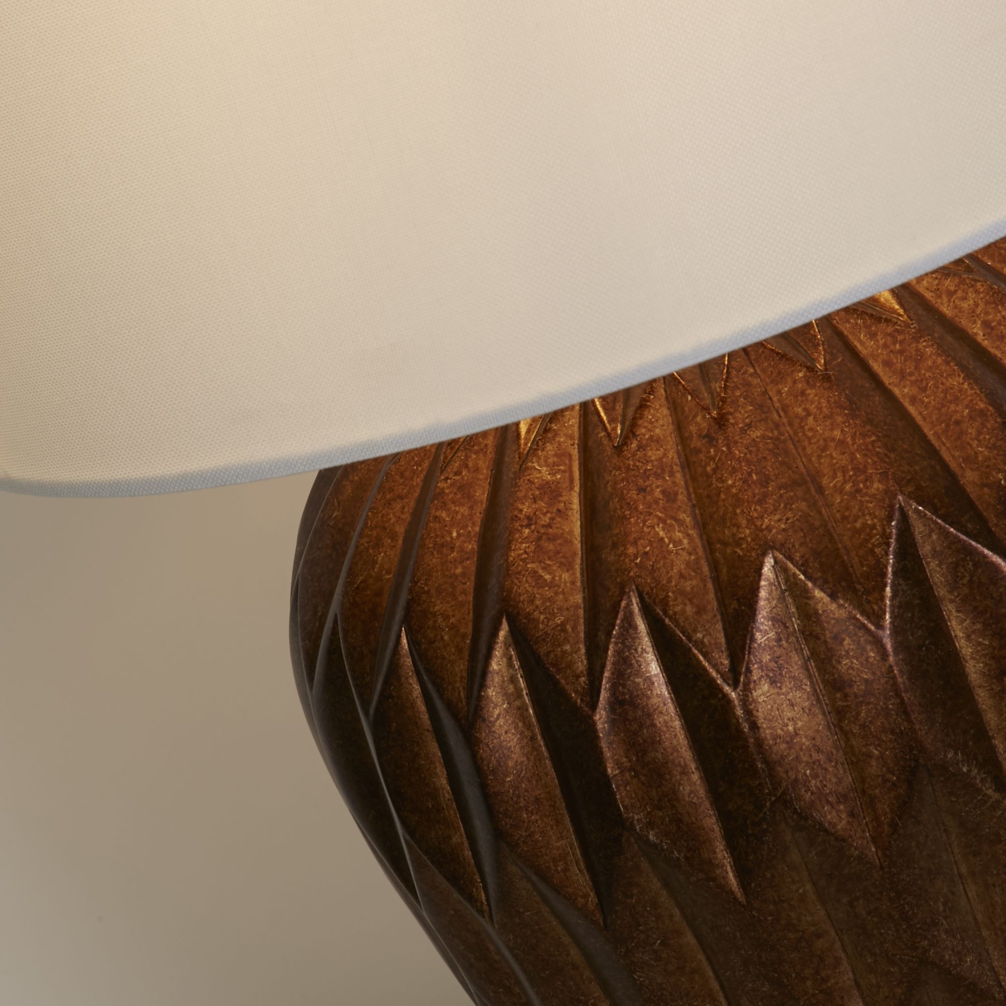 Close up of the Rosetta lamp's faceted bronze resin texture where the base meets the white linen shade