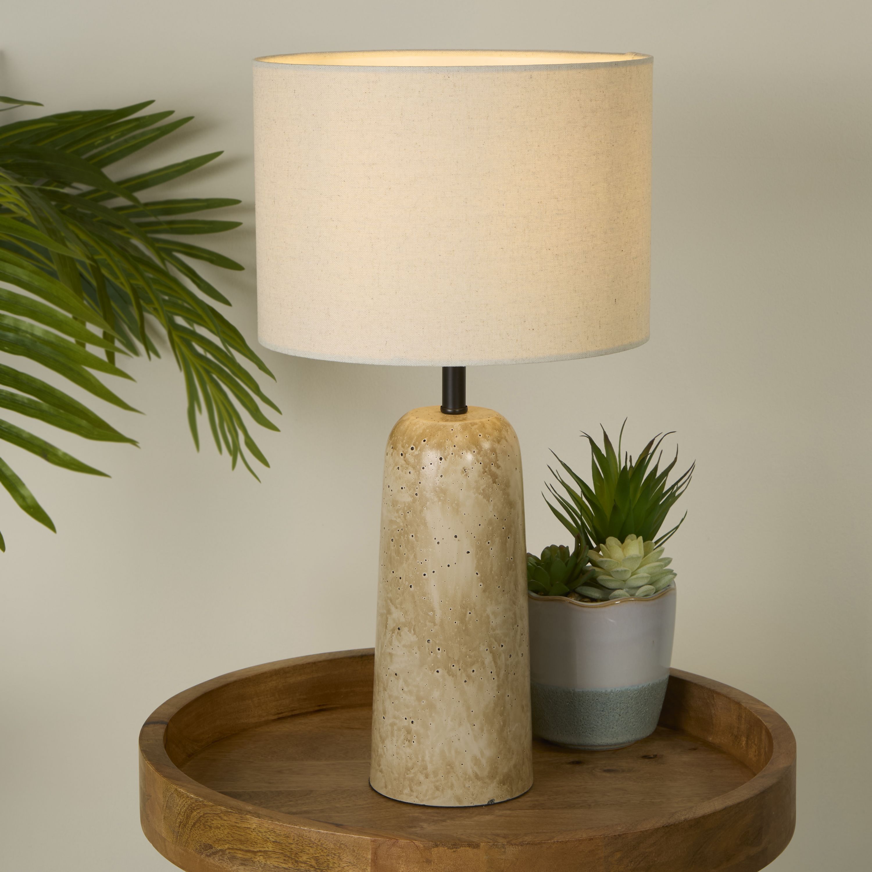 Agra table lamp styled on a round wooden side table next to a potted succulent