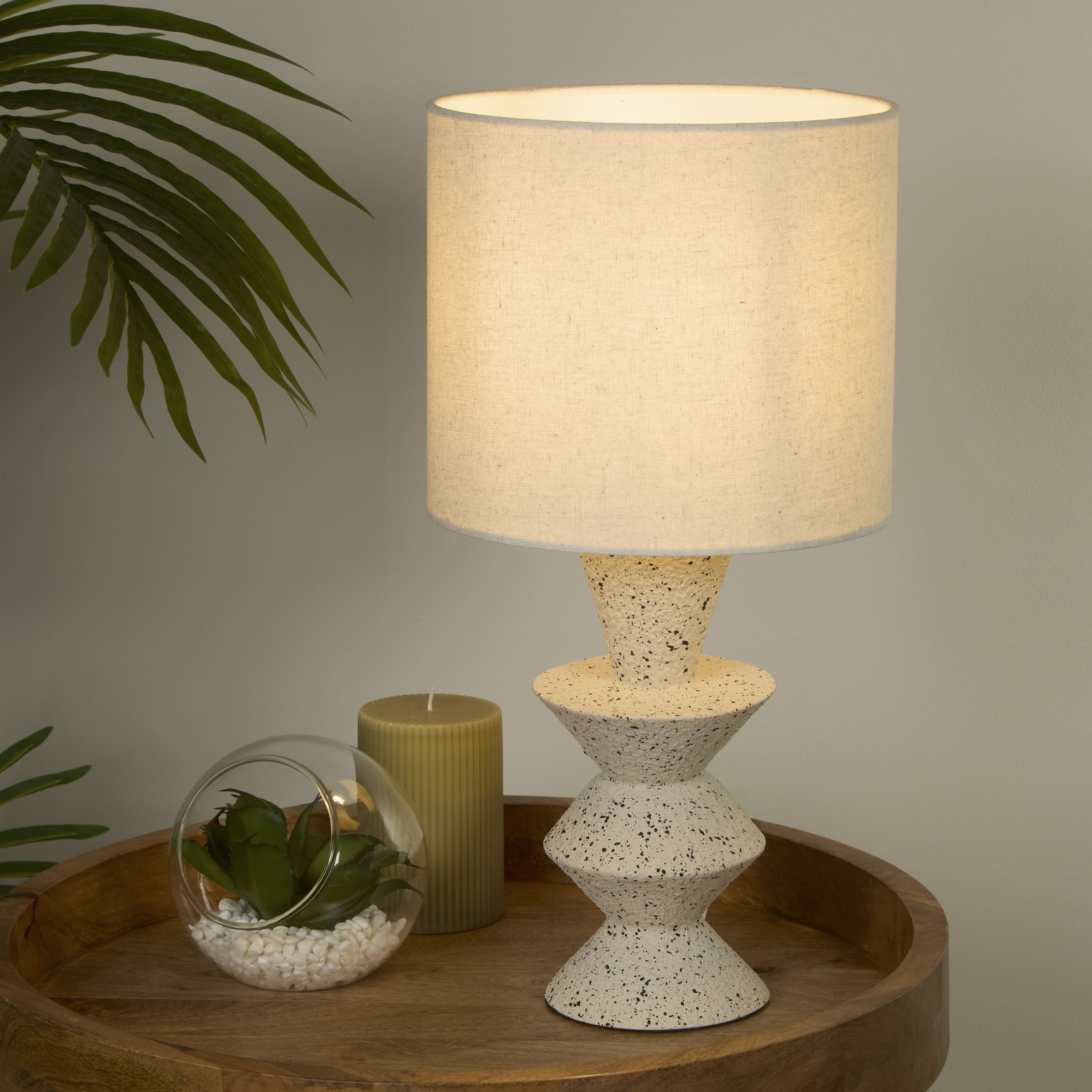Malacca table lamp styled on a round wooden tray table next to a candle and a glass terrarium