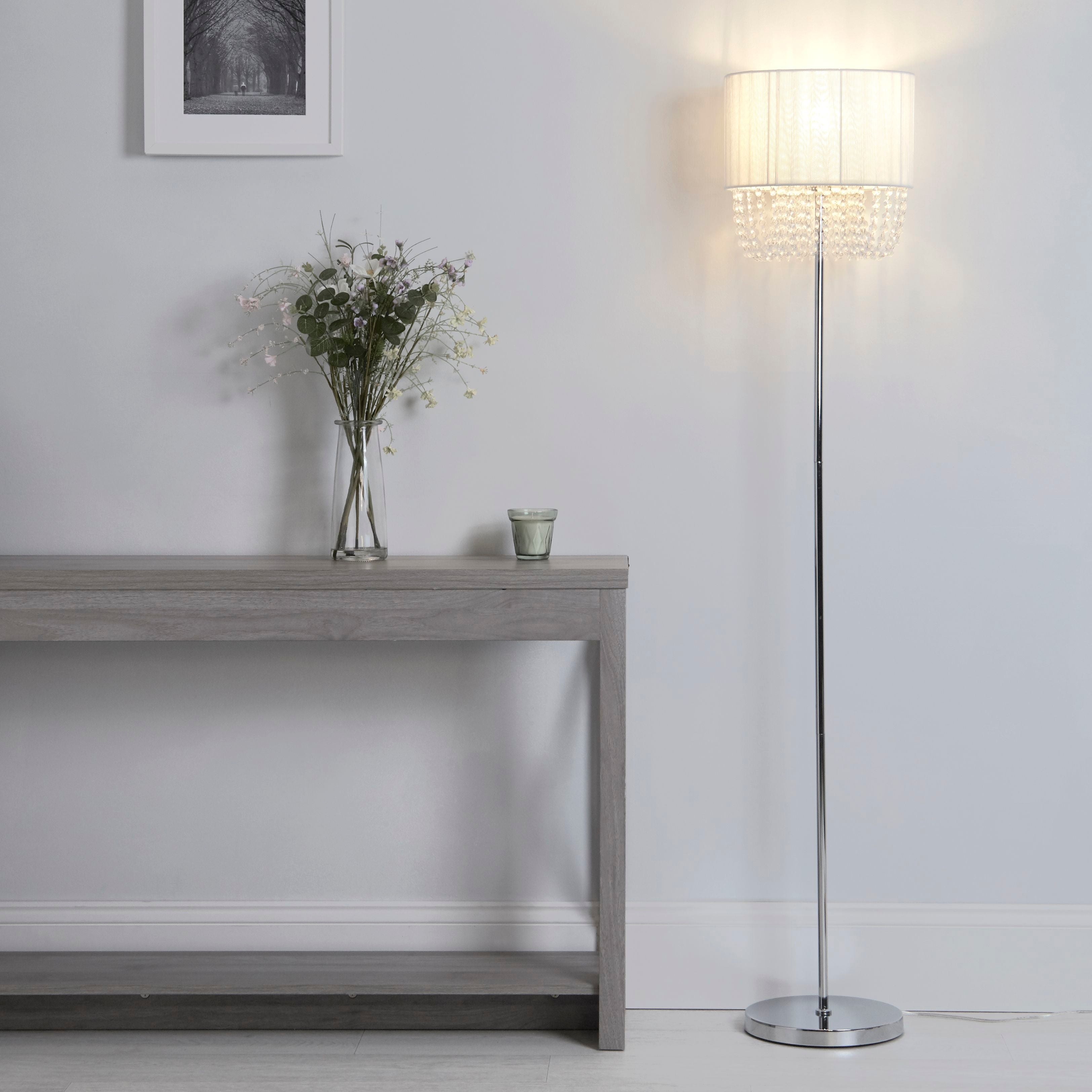 Bellano floor lamp with white beaded shade lit beside a console table in a hallway