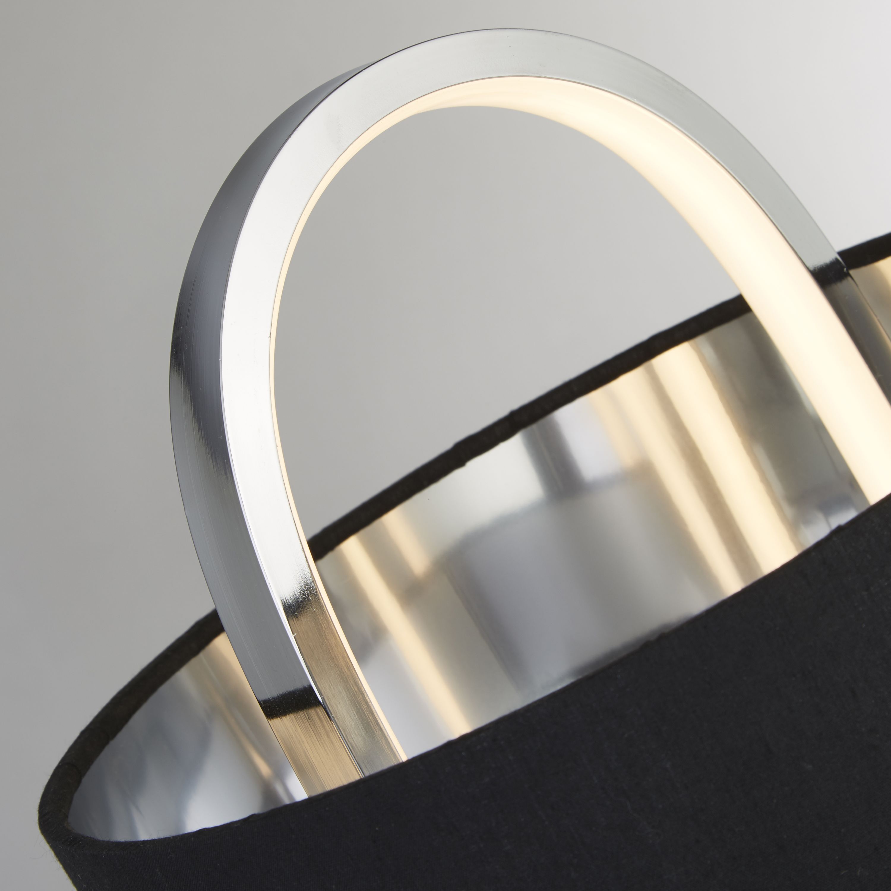 Close up of the Madrid table lamp's chrome ring, showing the glowing integrated LED strip and the fabric shade texture