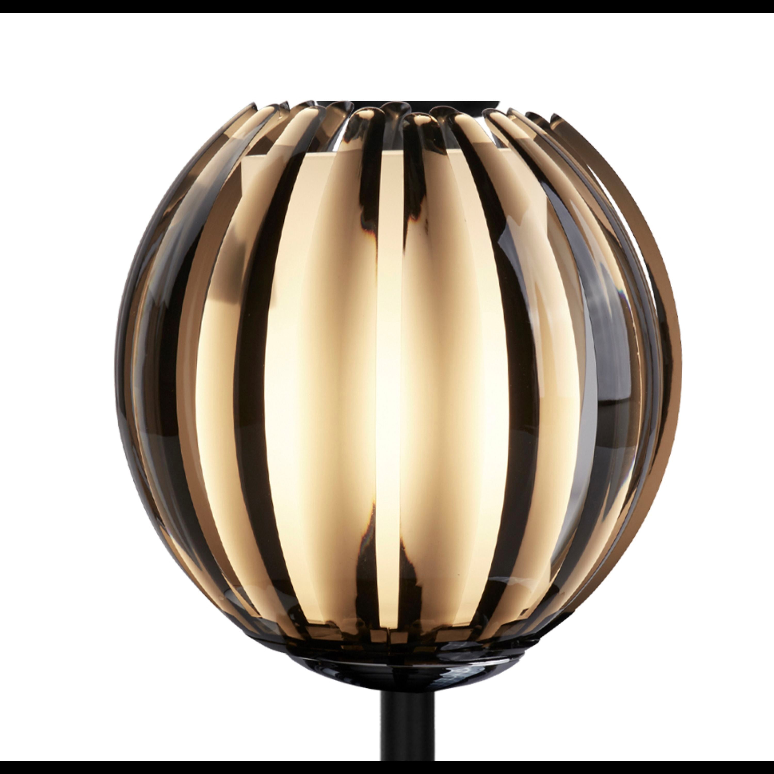 Close up of the curved smoked acrylic slats on the Blossom table lamp's globe shade, lit from within