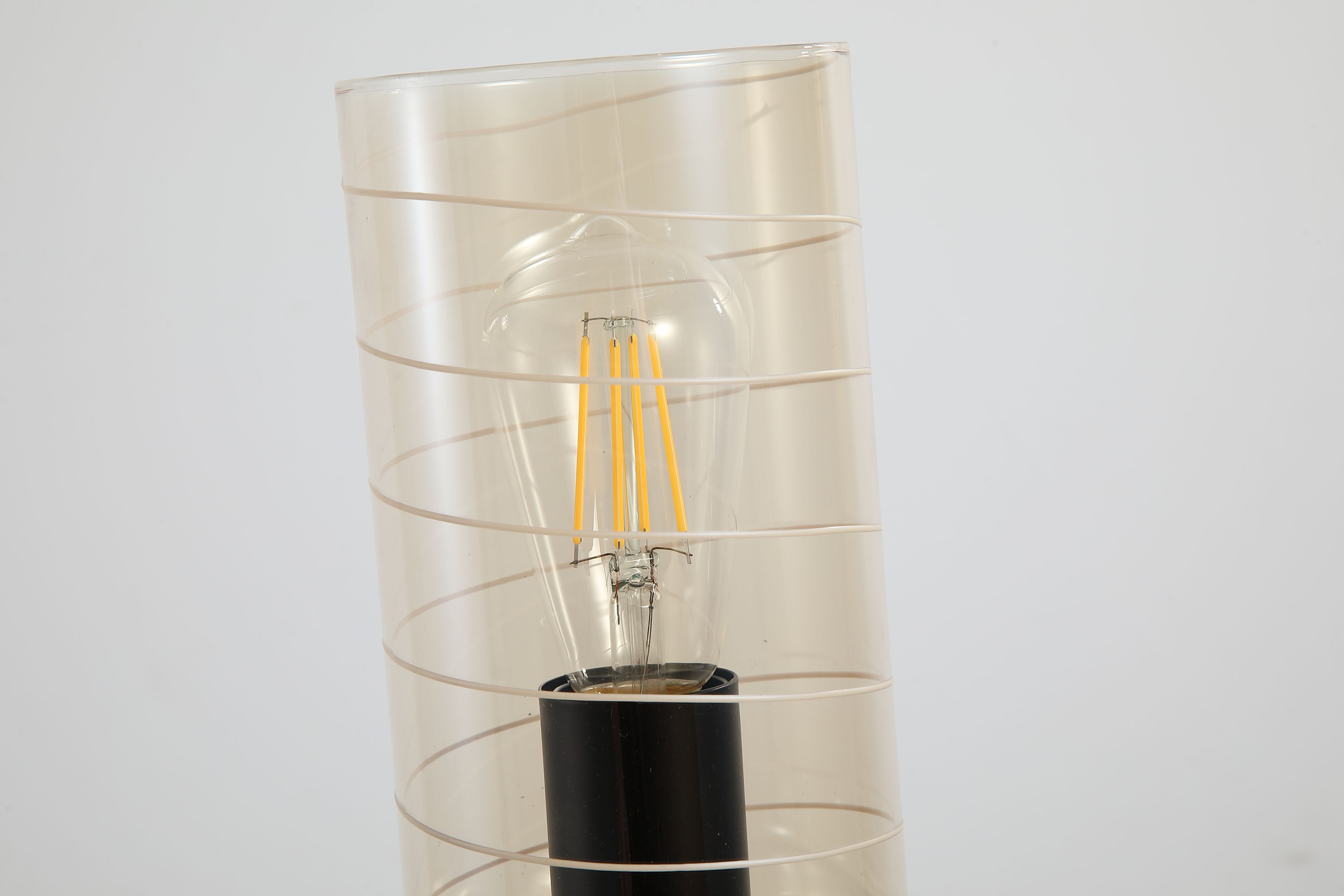 Close up of the exposed filament bulb and spiral line pattern on the amber glass of the Broughton table lamp