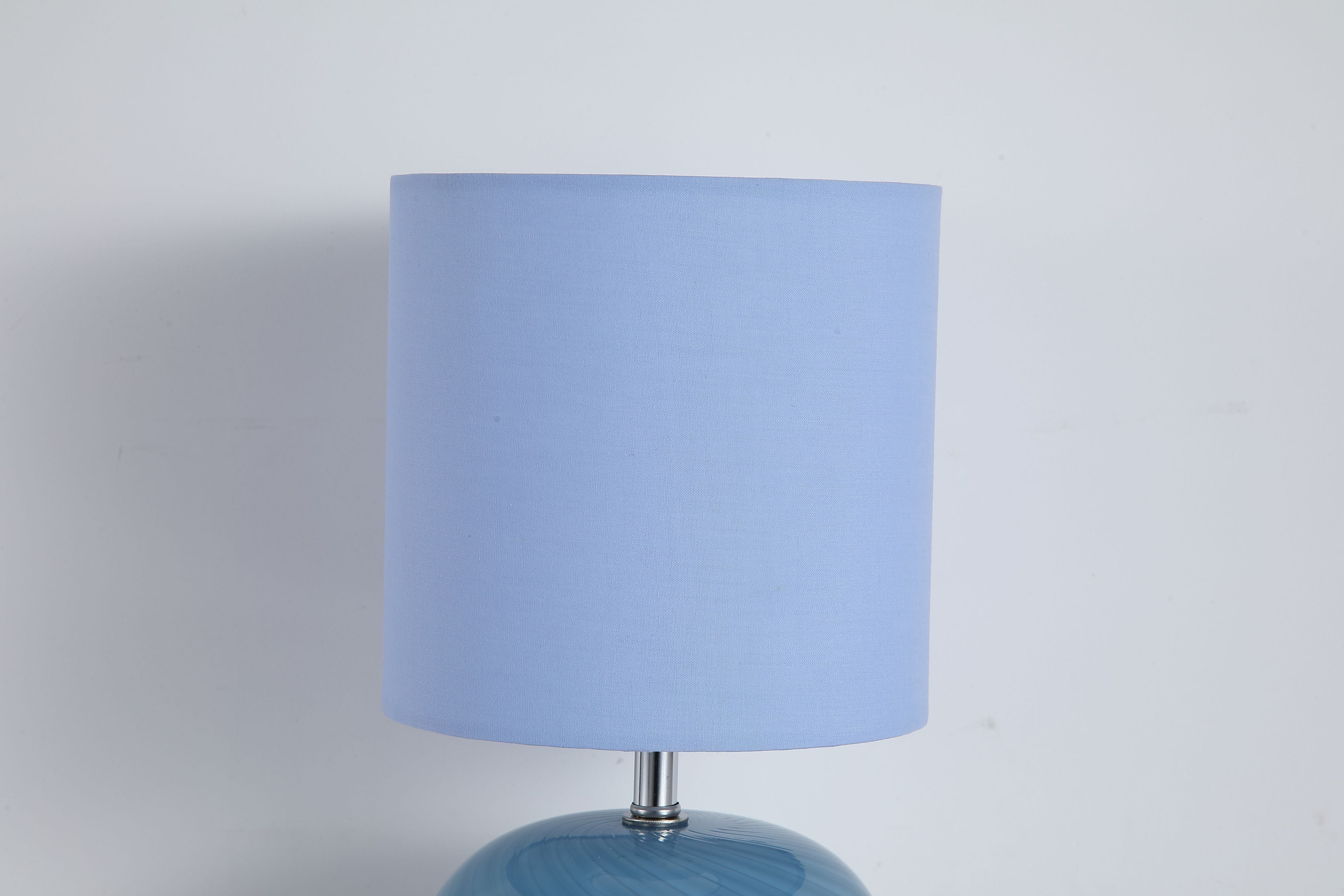 Extreme close up of the Fete lamp's blue linen shade fabric and top edge, cropped tight against a plain grey background
