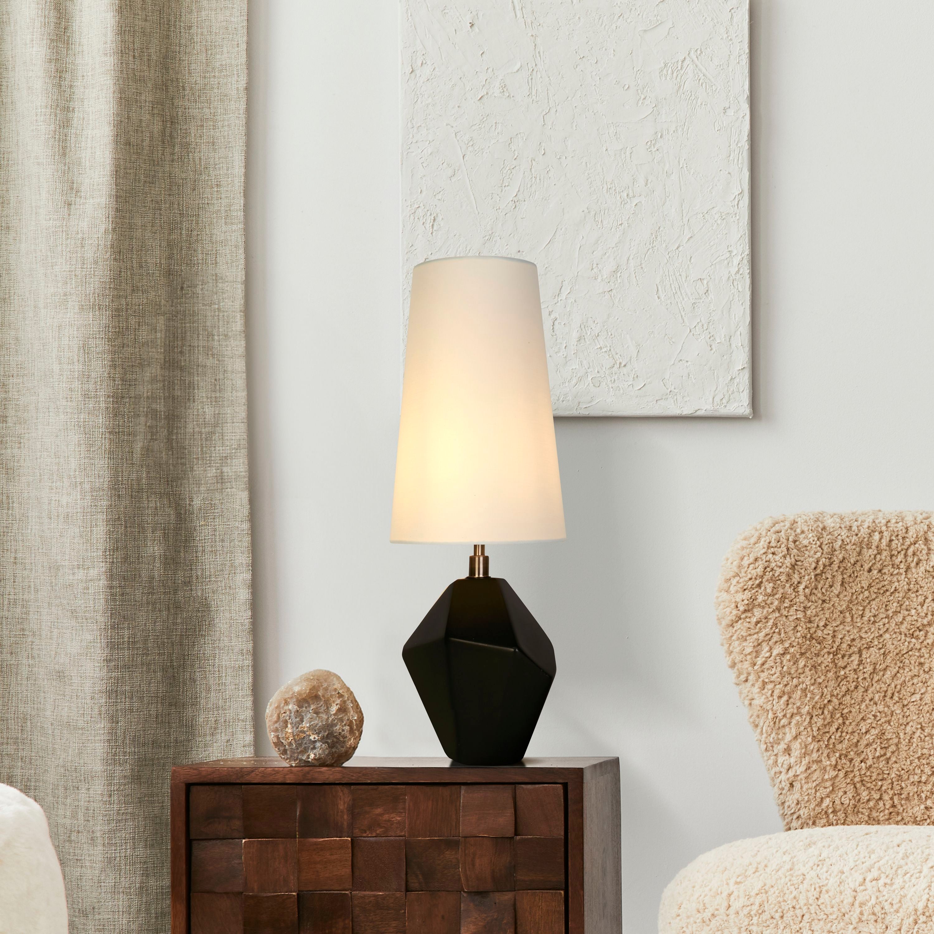 Apex black table lamp styled on a wooden woven cabinet next to a mineral stone ornament