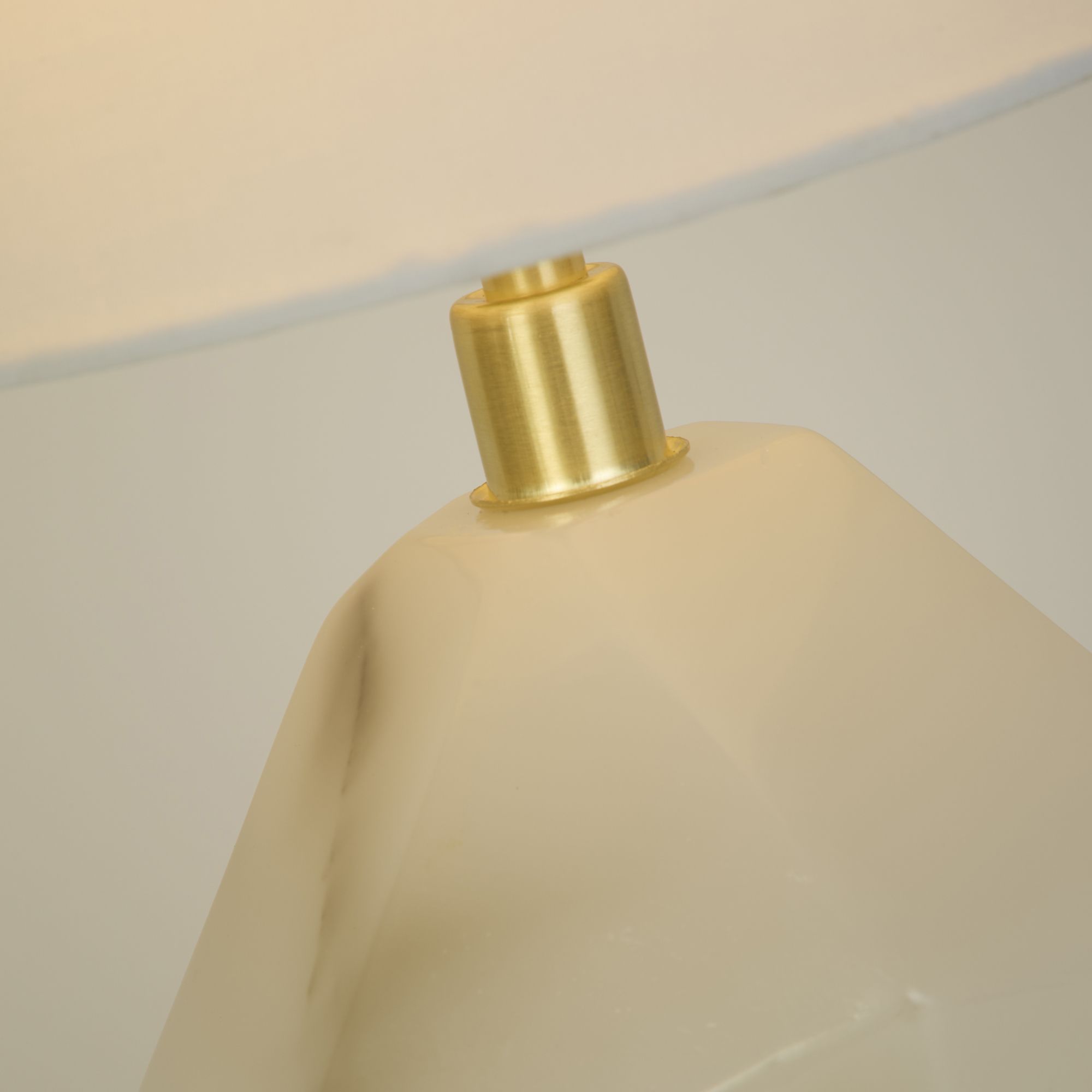 Close up of the Apex table lamp neck showing the satin brass fitting against the white marbled resin base