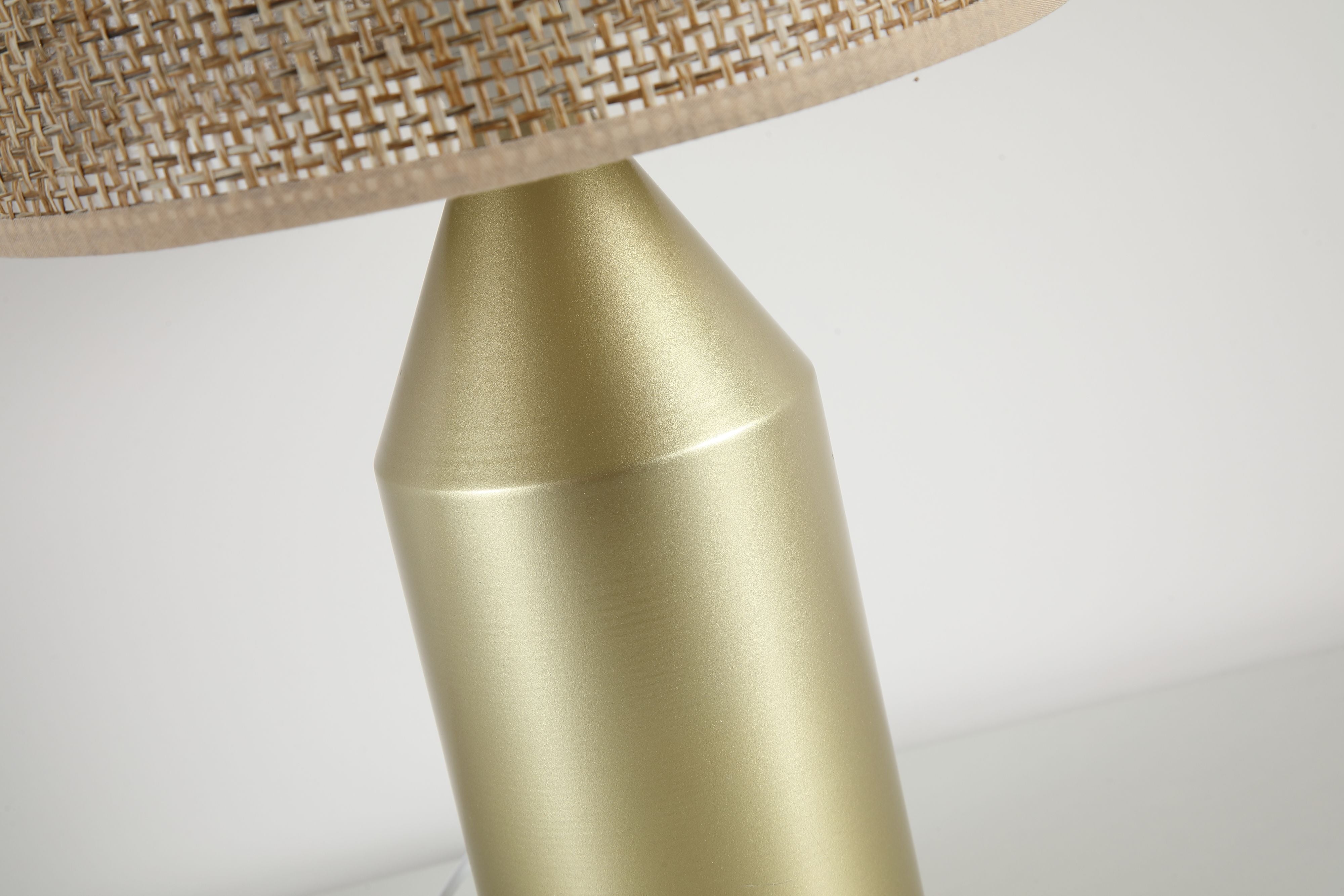 Close up of the Pheobe lamp's gold metal neck and base beneath the woven rattan shade