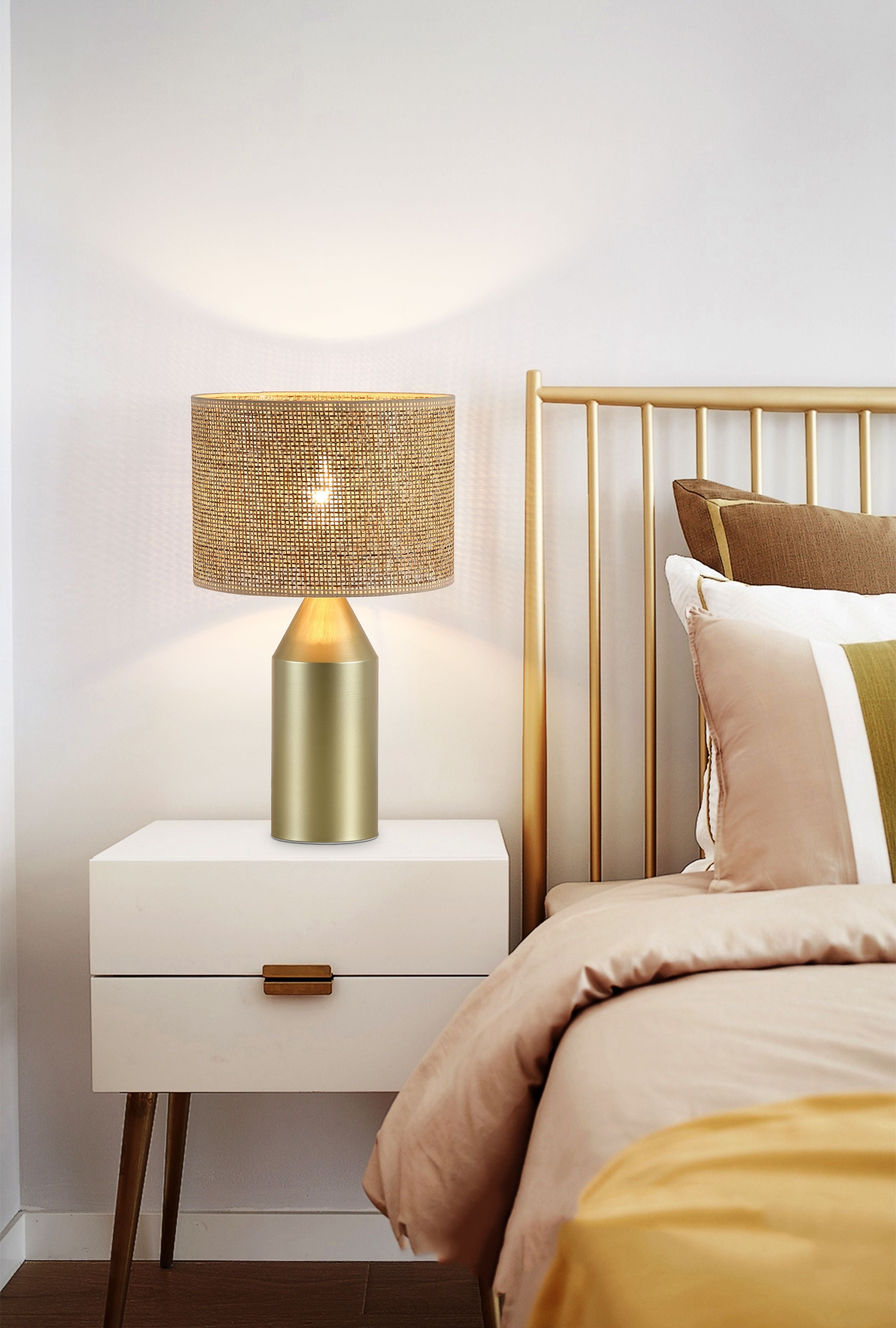 Pheobe gold table lamp with rattan shade styled on a white bedside table next to a gold bed frame