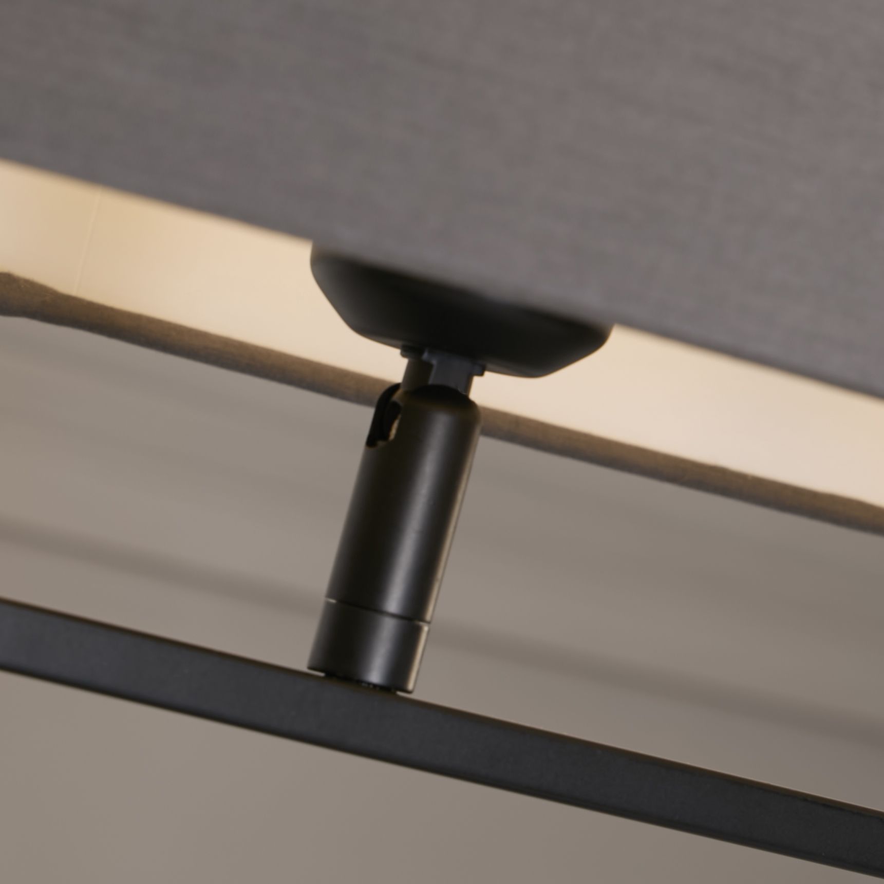 Close up of the Sleek table lamp's black finial and lamp holder where the grey shade meets the metal base.