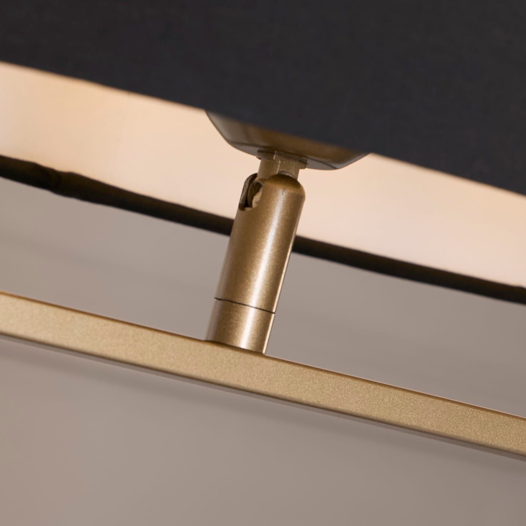 Close up of the Sleek table lamp's bronze finial and lamp holder where the black shade meets the bronze metal base.