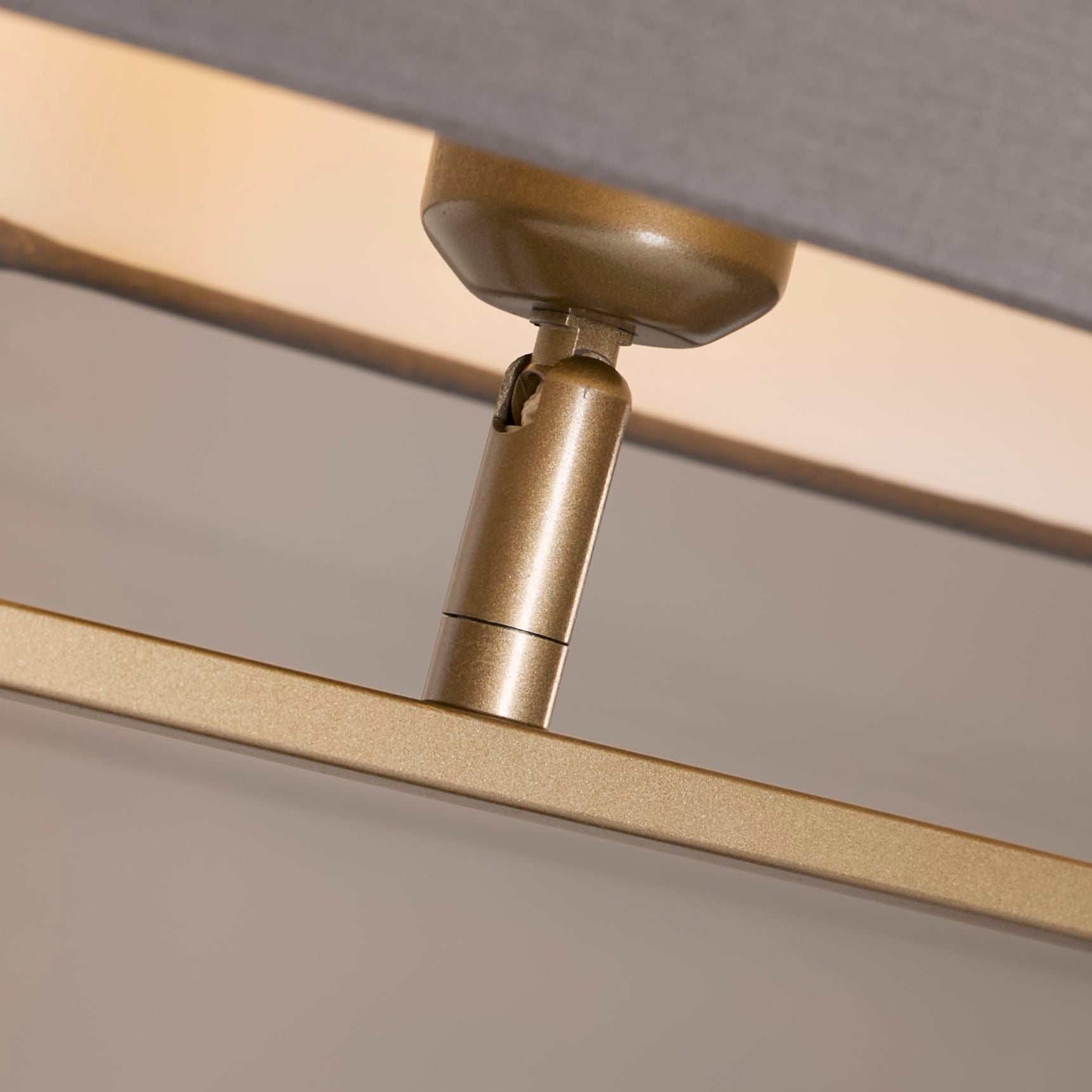 Close up of the Sleek table lamp's bronze finial and lamp holder where the grey shade meets the bronze metal base.
