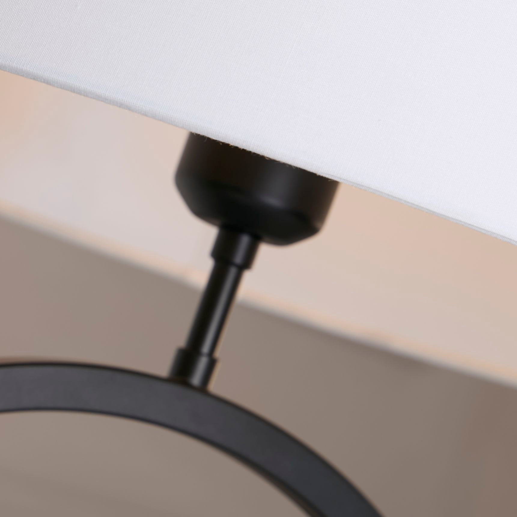 Close up of the black collar joint connecting the white cotton shade to the matt black ring base