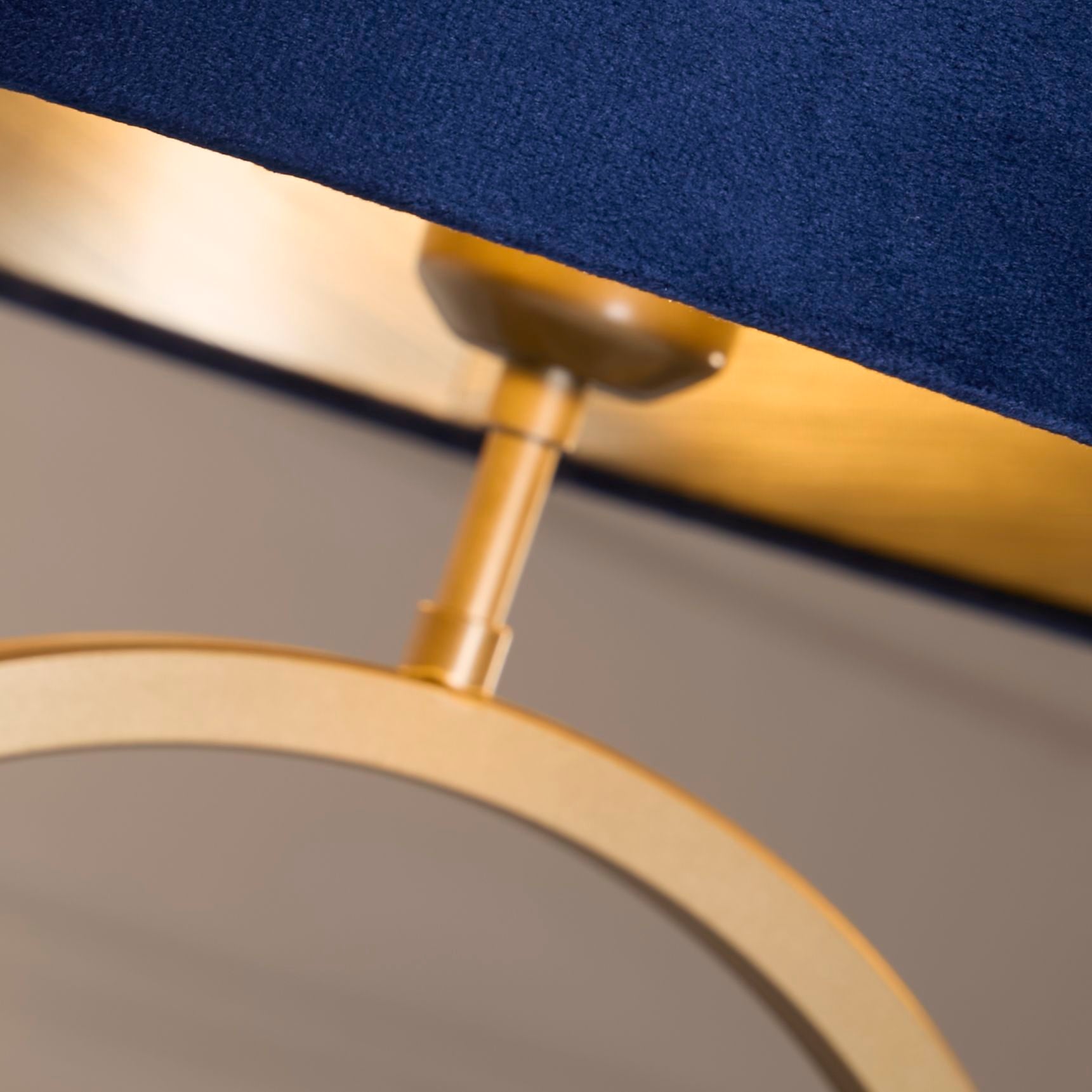 Close up of the bronze ring base and bulb holder beneath the navy velvet shade, showing the metal finish and velvet texture