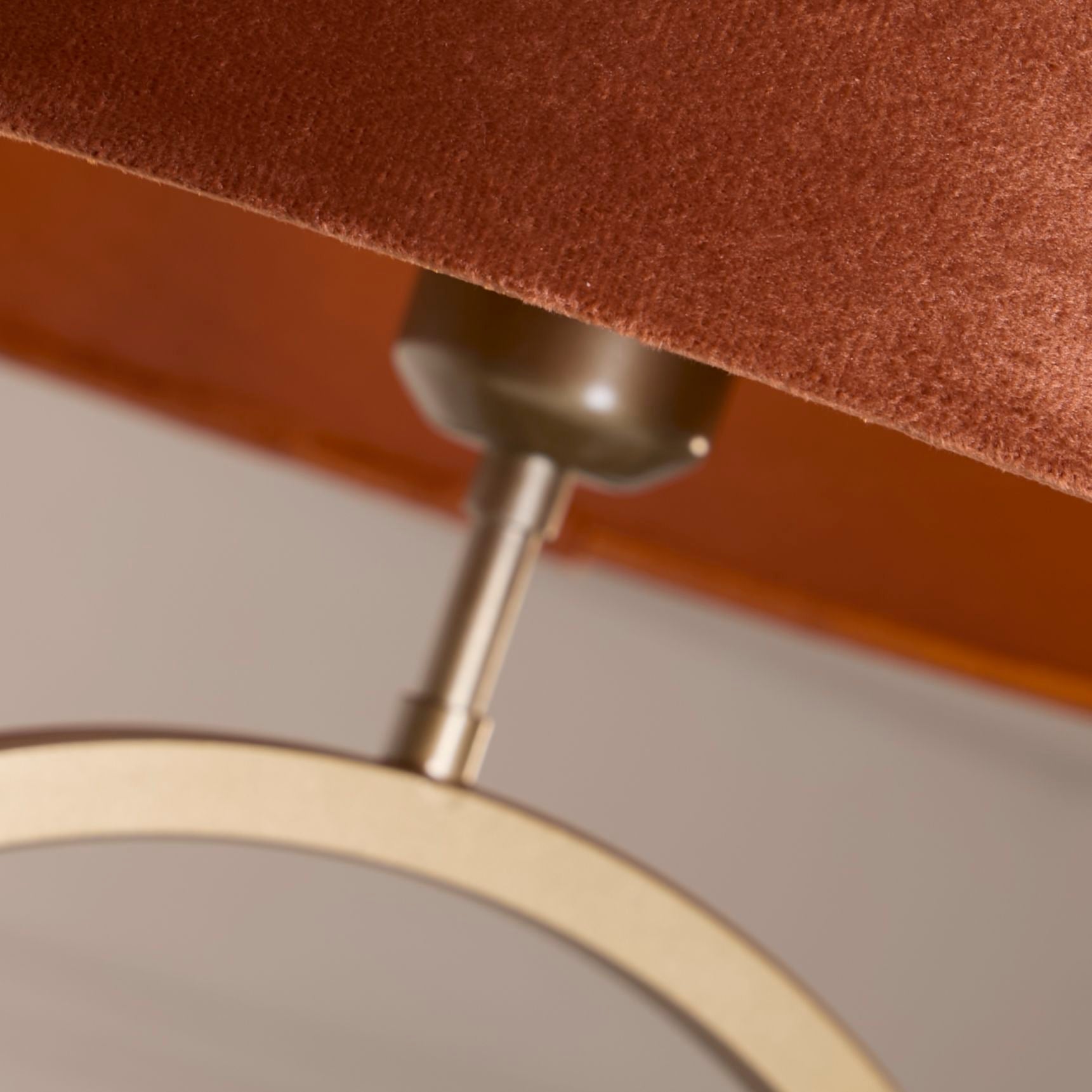 Close up of the bronze ring base and bulb holder beneath the burnt orange velvet shade, showing the metal finish and velvet texture