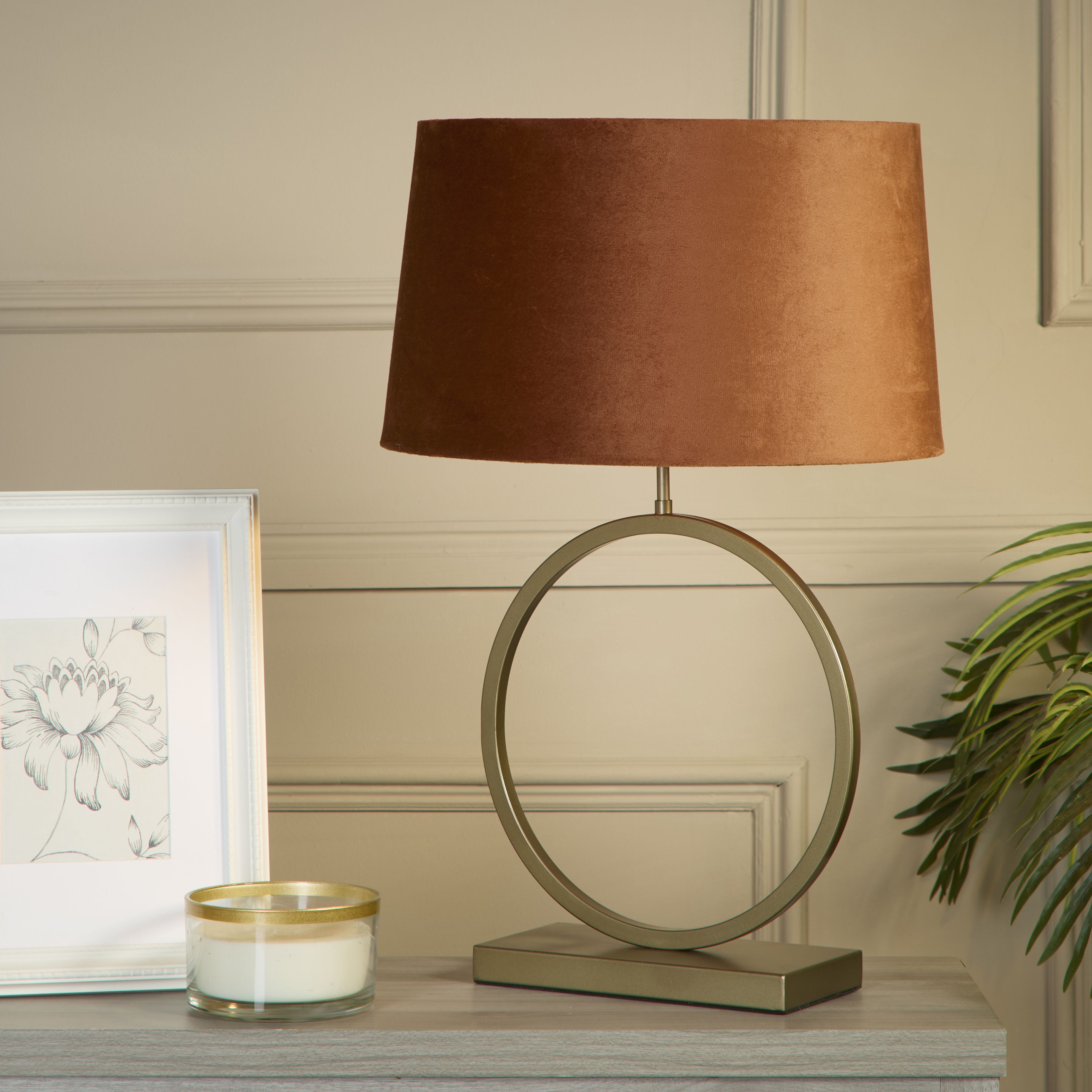 Elegant table lamp with burnt orange velvet shade styled on a console table with a framed botanical print, candle and trailing plant