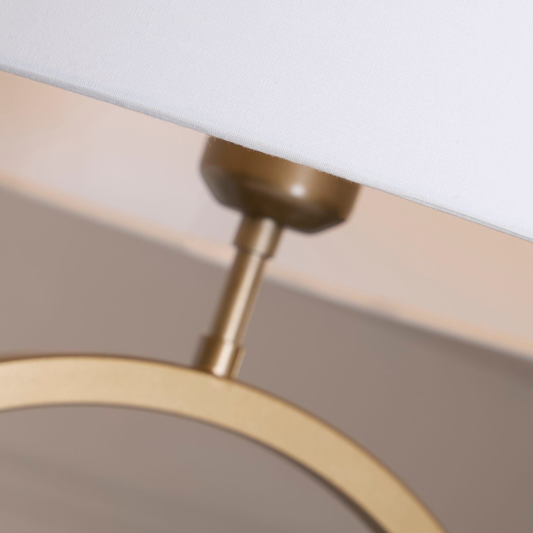 Close up of the bronze ring base and bulb holder beneath the white cotton shade, showing the metal finish