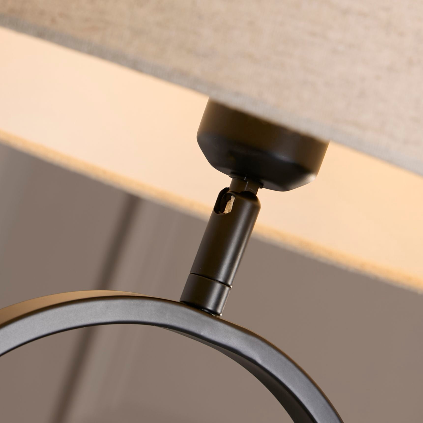 Close up of the brass adjustable joint connecting the natural linen shade to the matt black oval base